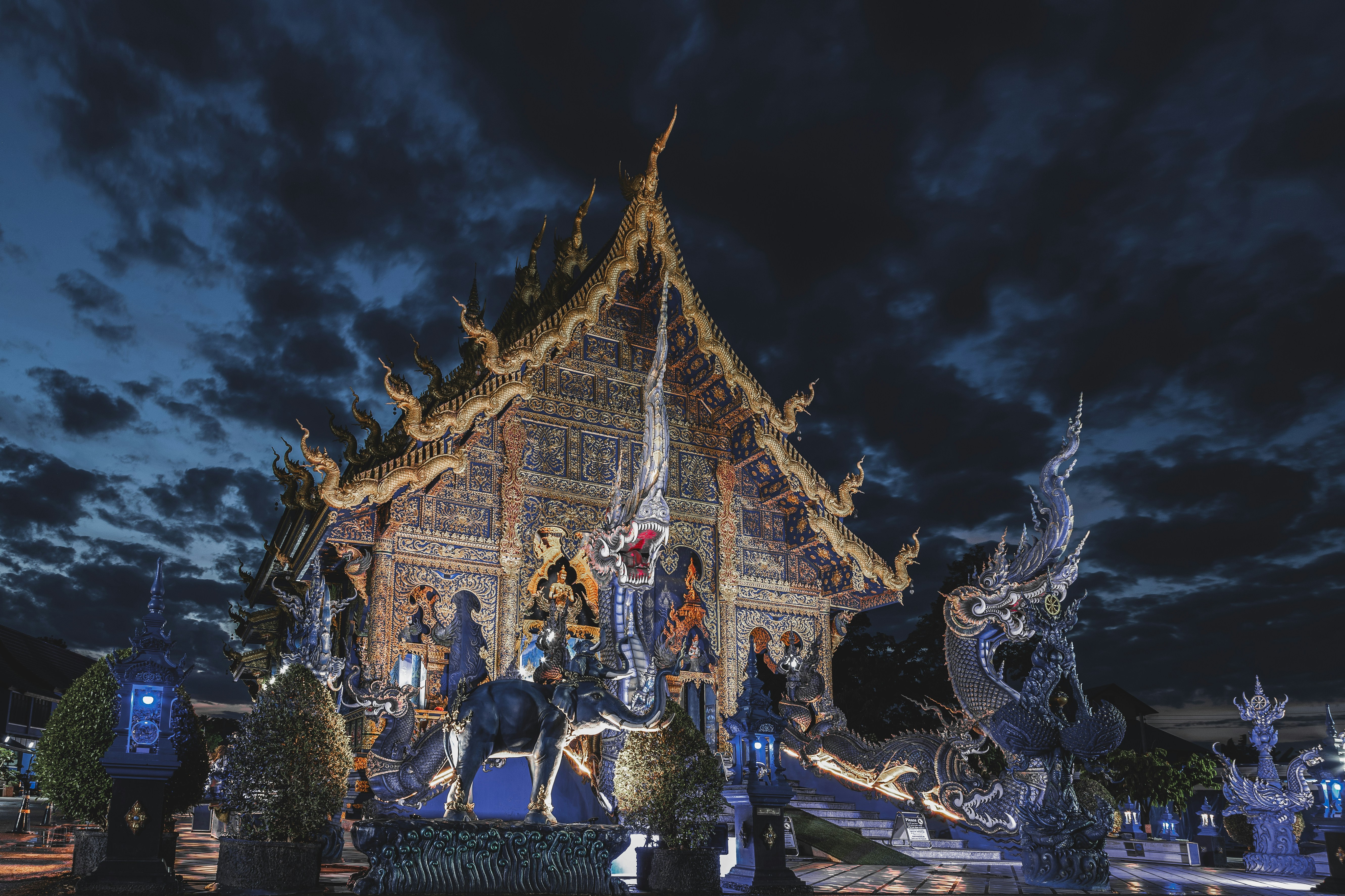 Ornate temple illuminated at night under cloudy sky