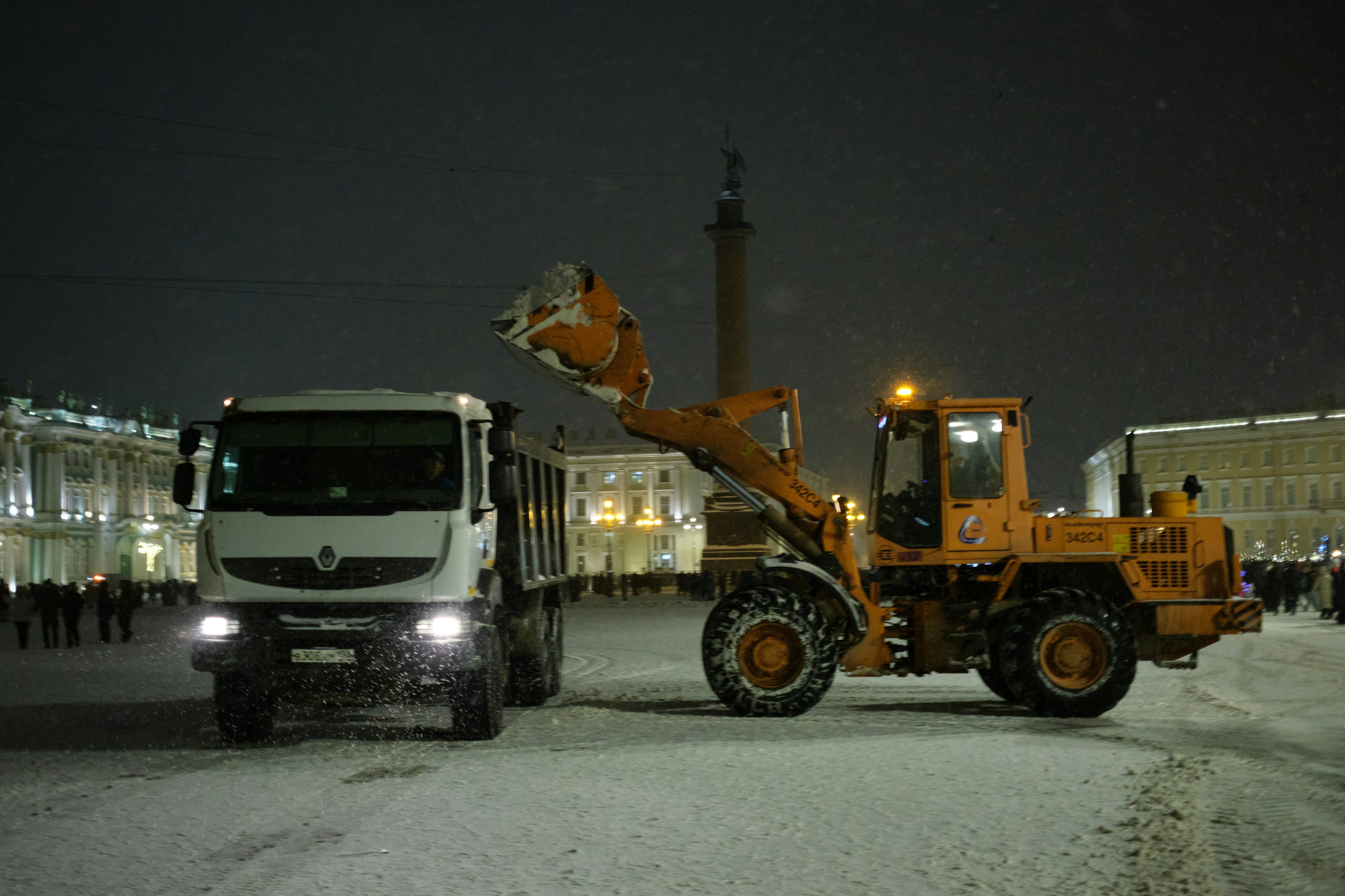 Loader dumps snow into truck at night