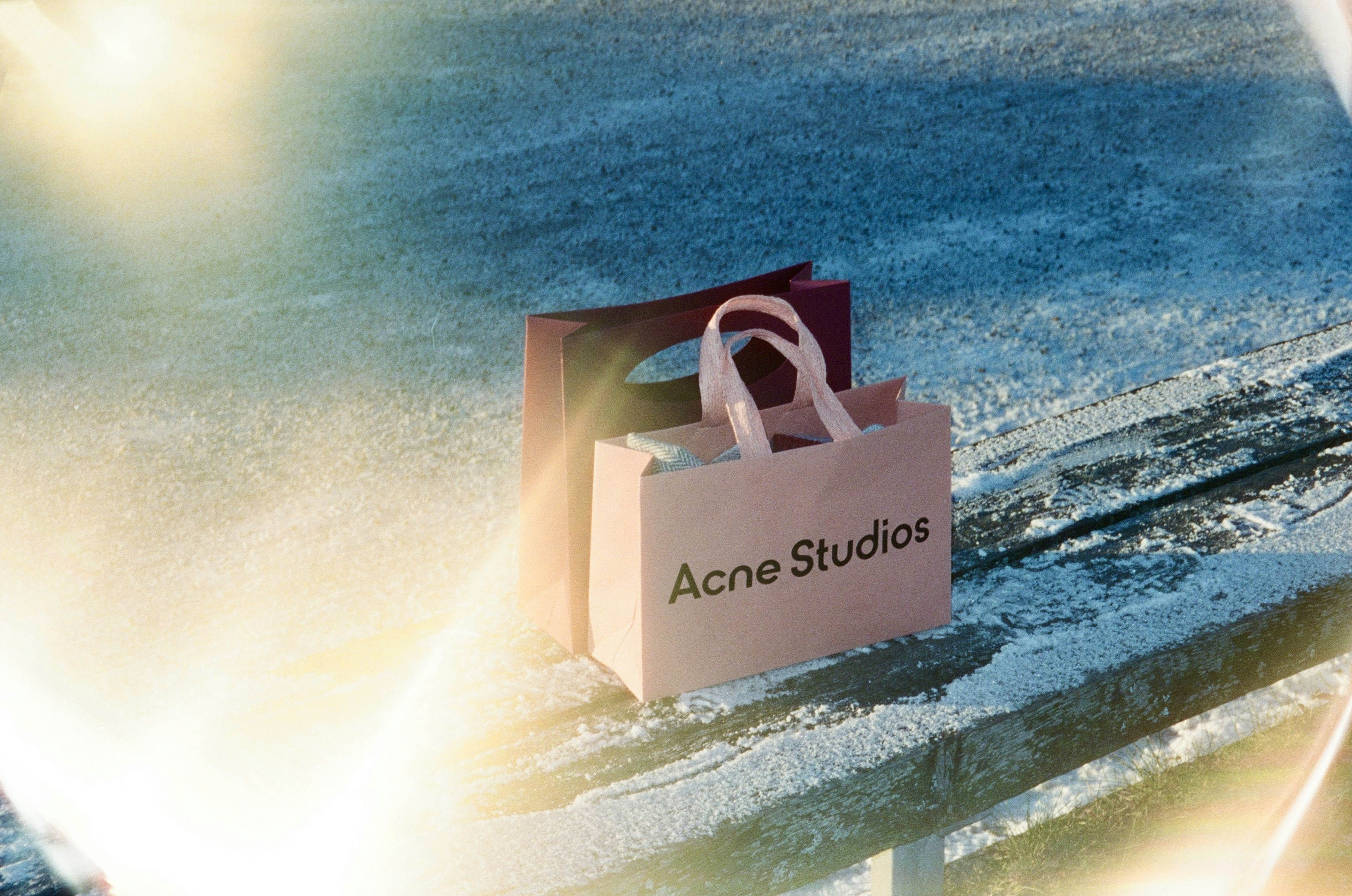 Two shopping bags on a snowy bench