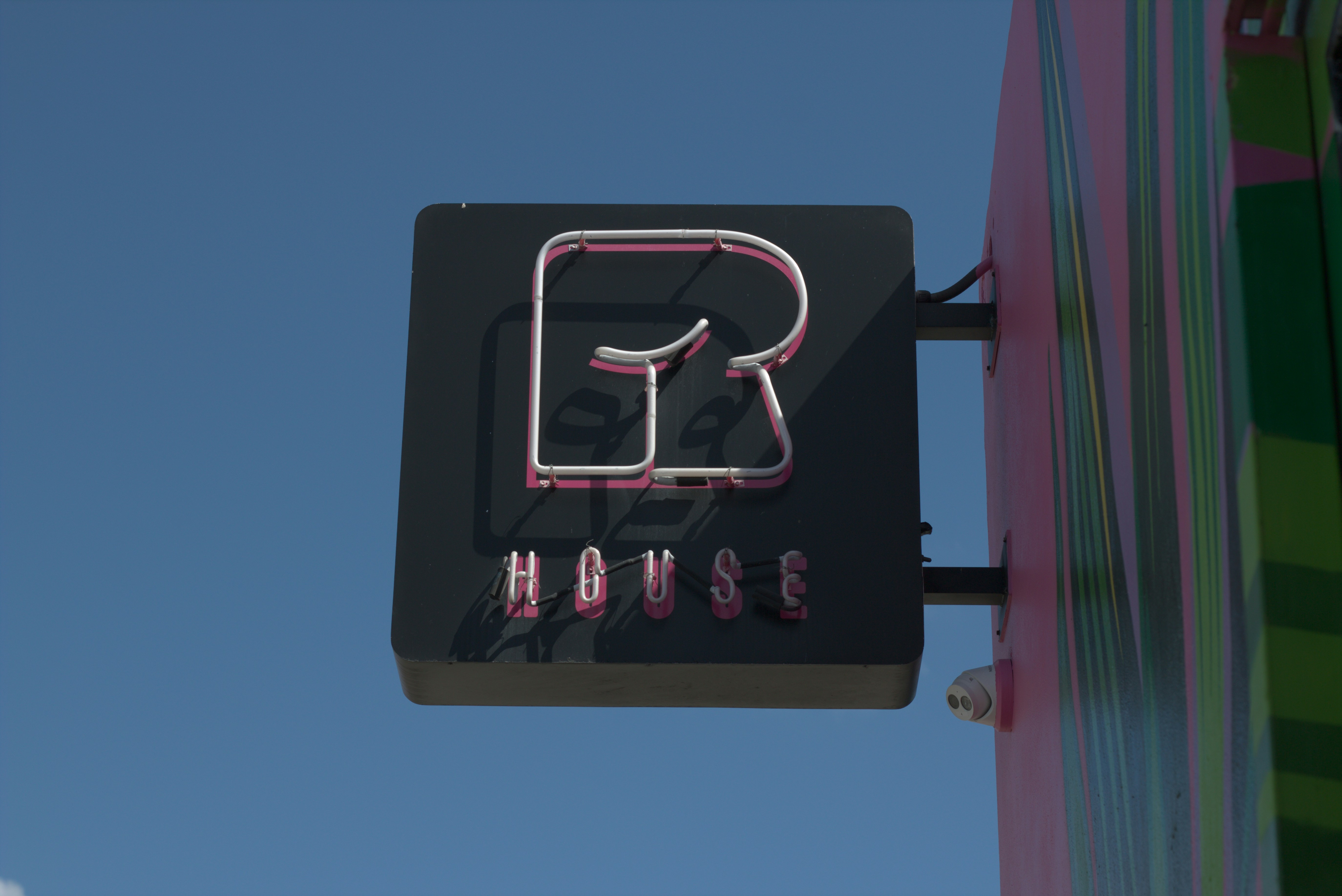 Neon sign for r house against blue sky