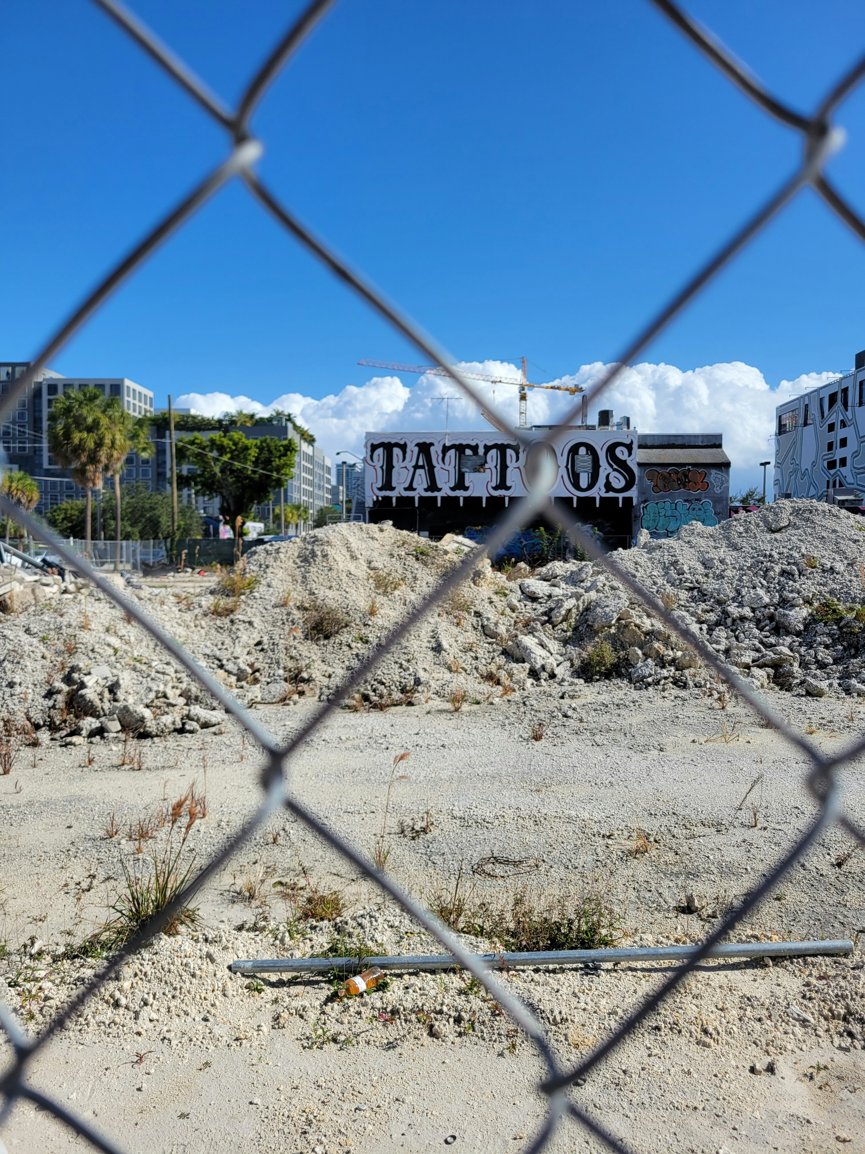 Building with "tattos" graffiti seen through fence.