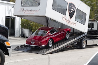 Red vintage car being loaded onto a car carrier.