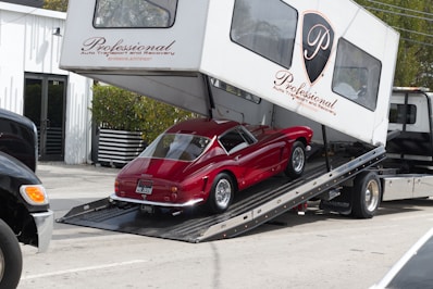 Red vintage car being loaded onto a car carrier.