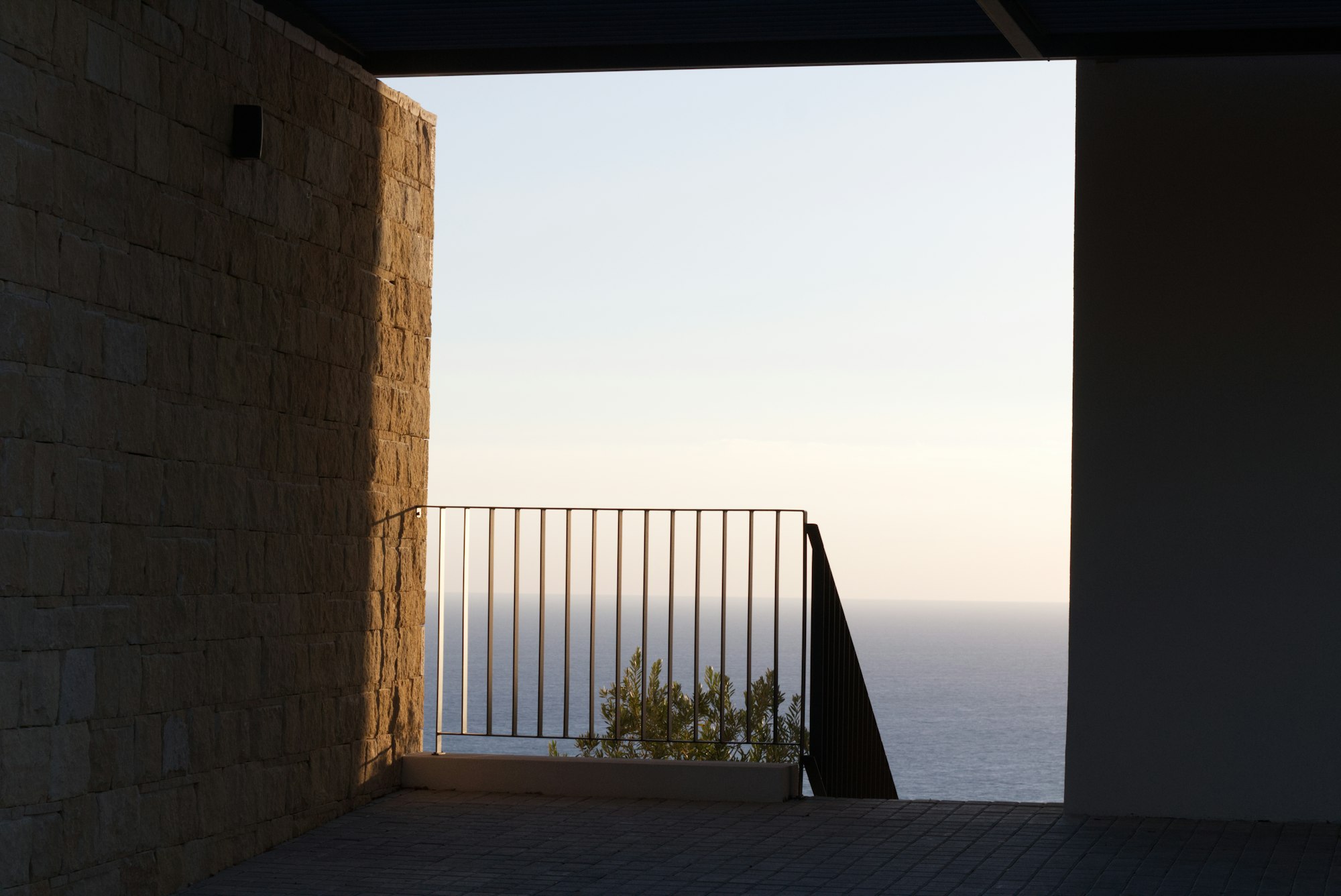 A balcony looking out over a calm ocean at dusk