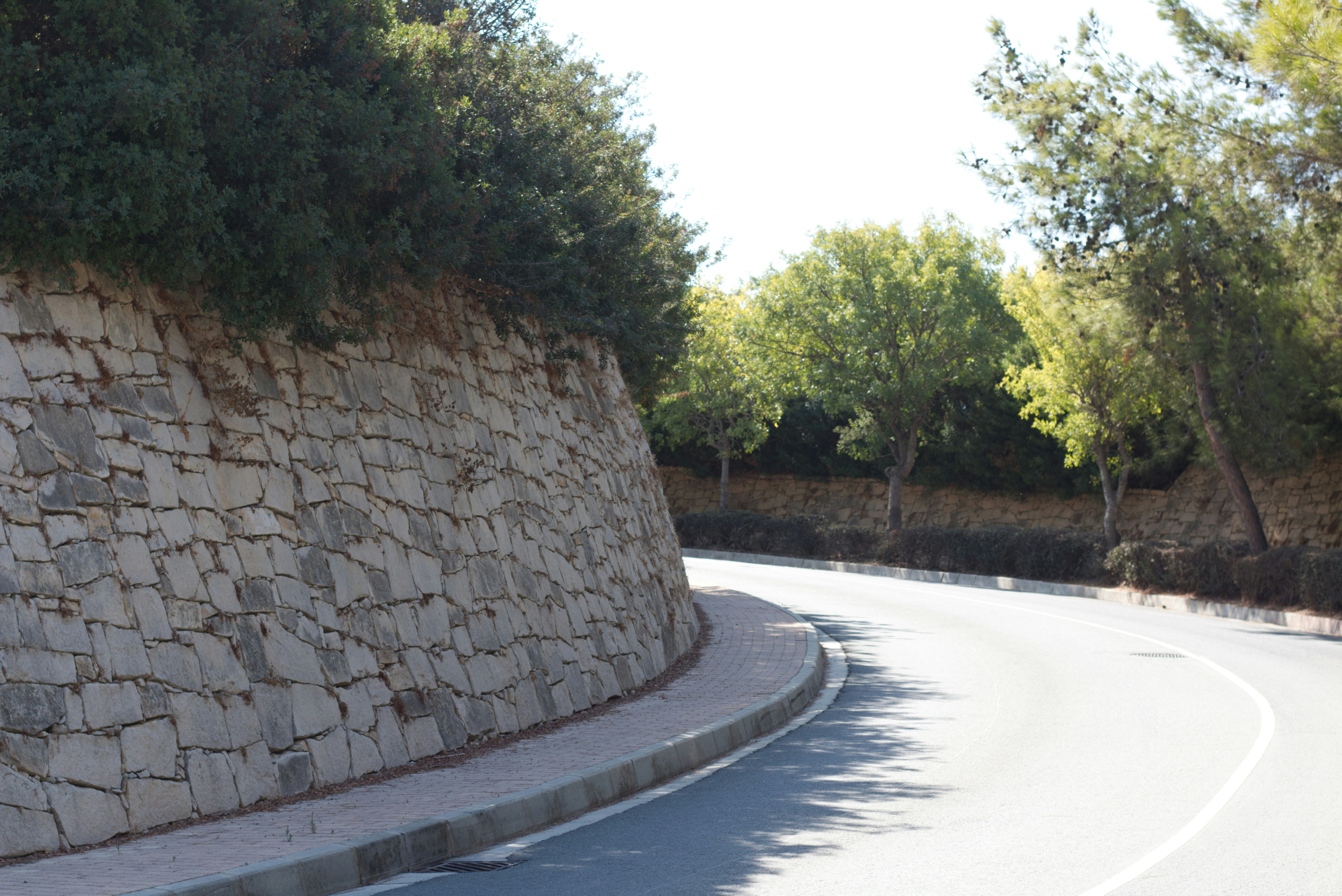 Estrada curva ao lado de um muro de contenção de pedra