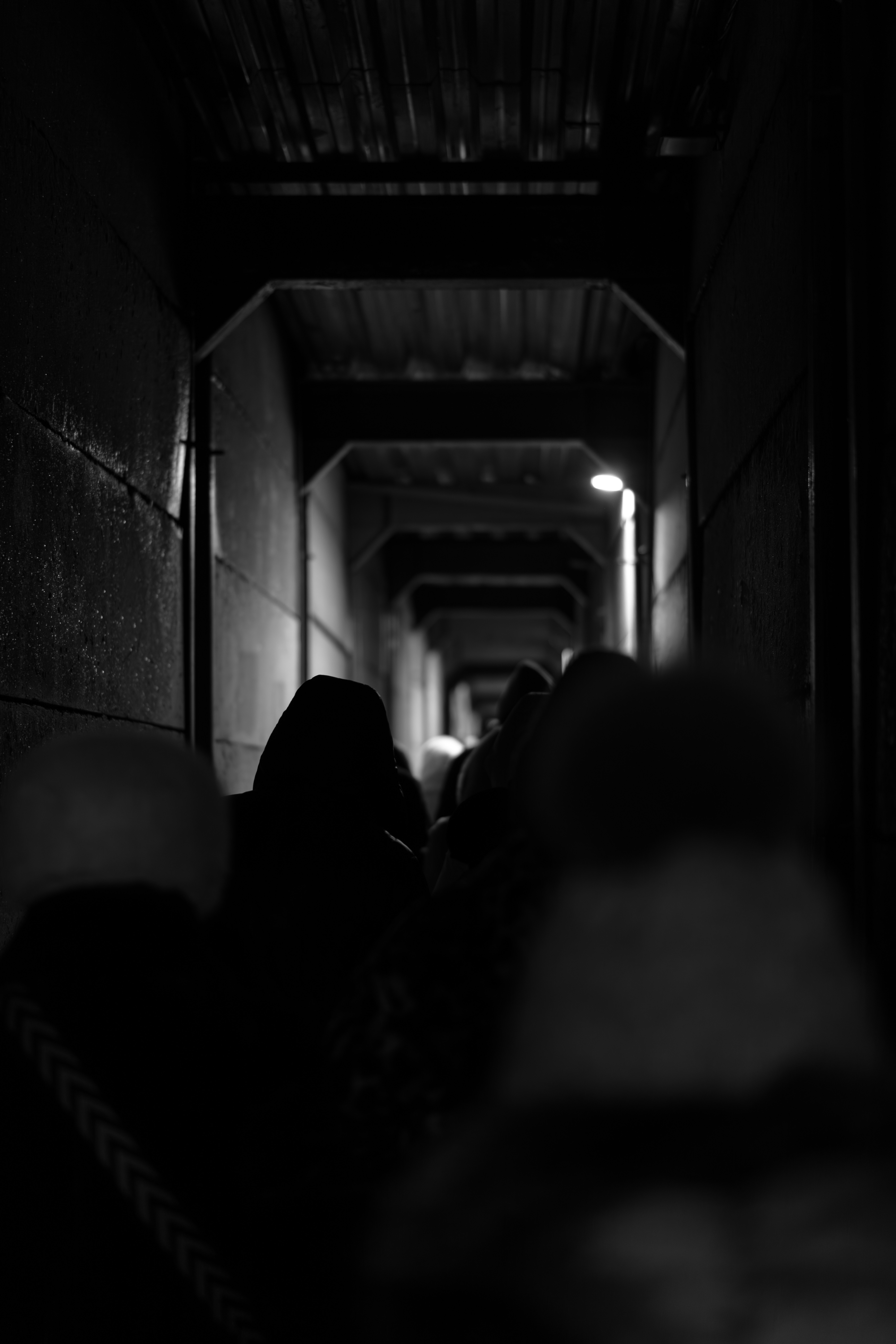 People walking down a dark, narrow hallway