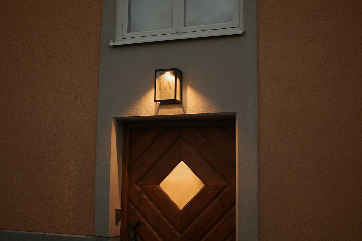 Porte d'entrée en bois éclairée à la tombée de la nuit - Guardiens
