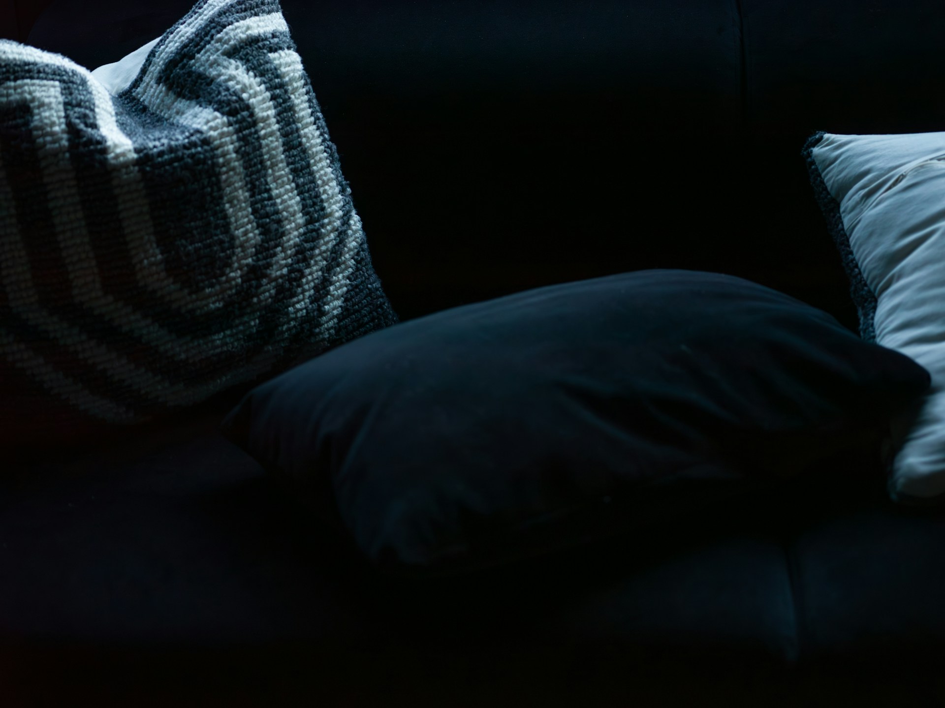 Three decorative pillows on a dark sofa
