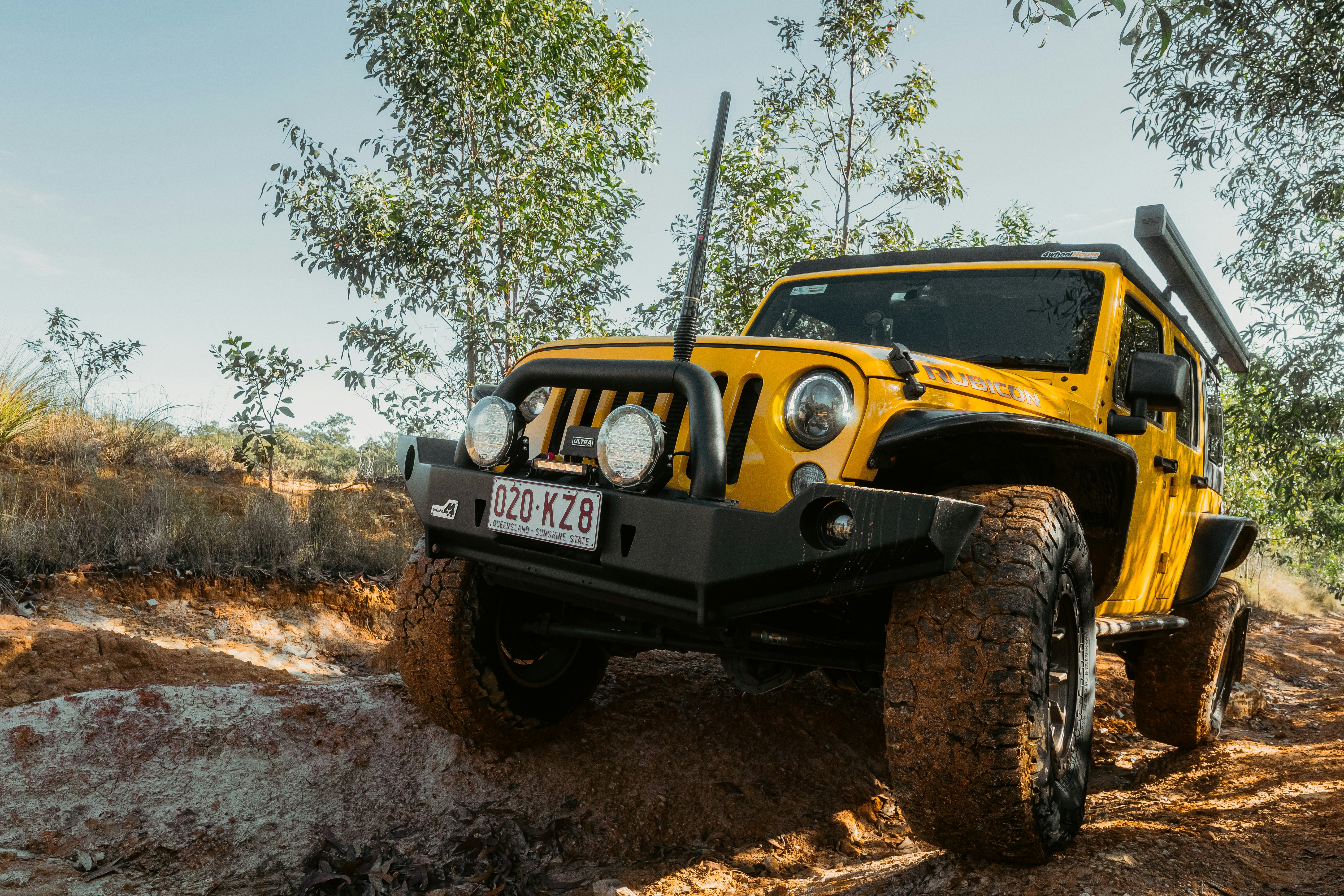 Yellow jeep driving on a muddy off-road trail