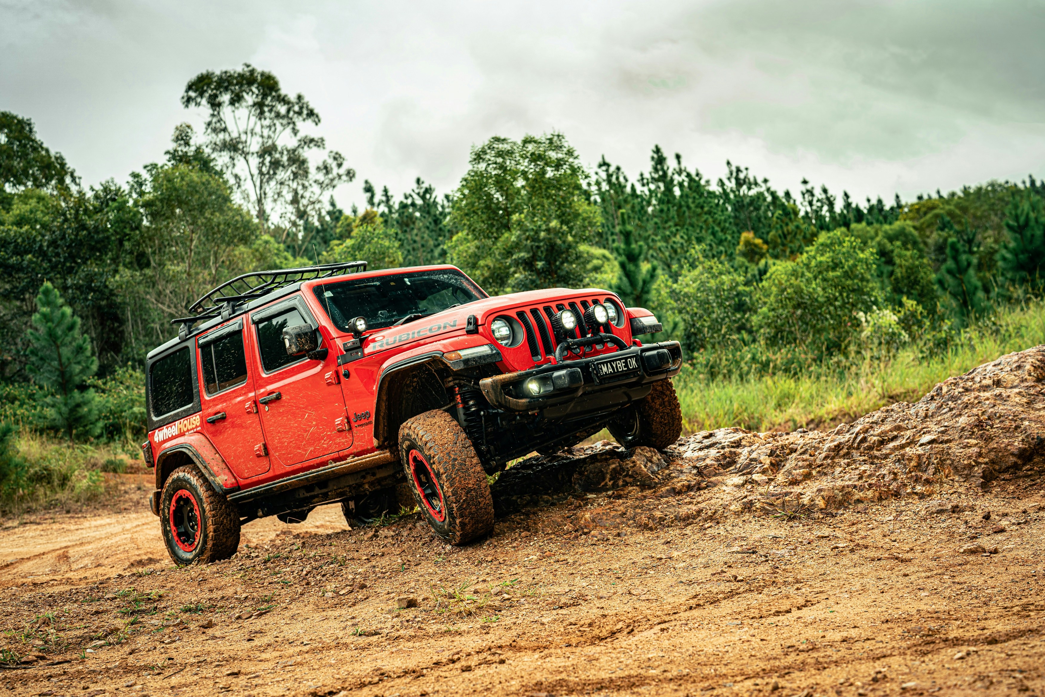Red jeep wrangler driving on a dirt hill.