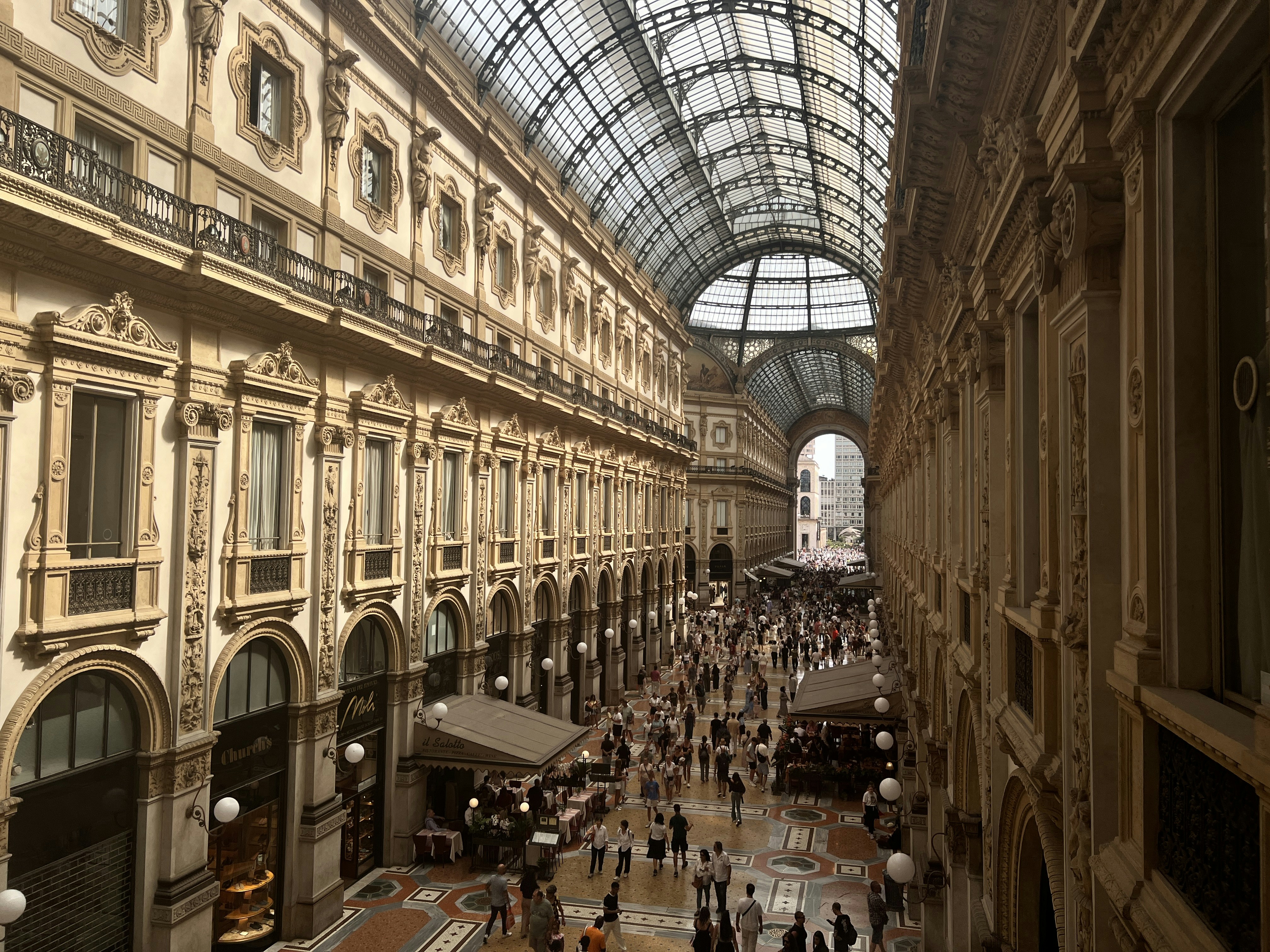 Elegant indoor shopping arcade with ornate architecture and crowds
