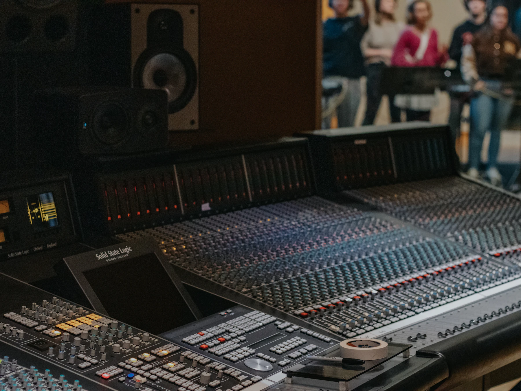Recording studio mixing console with people in the background used as representative service imagery