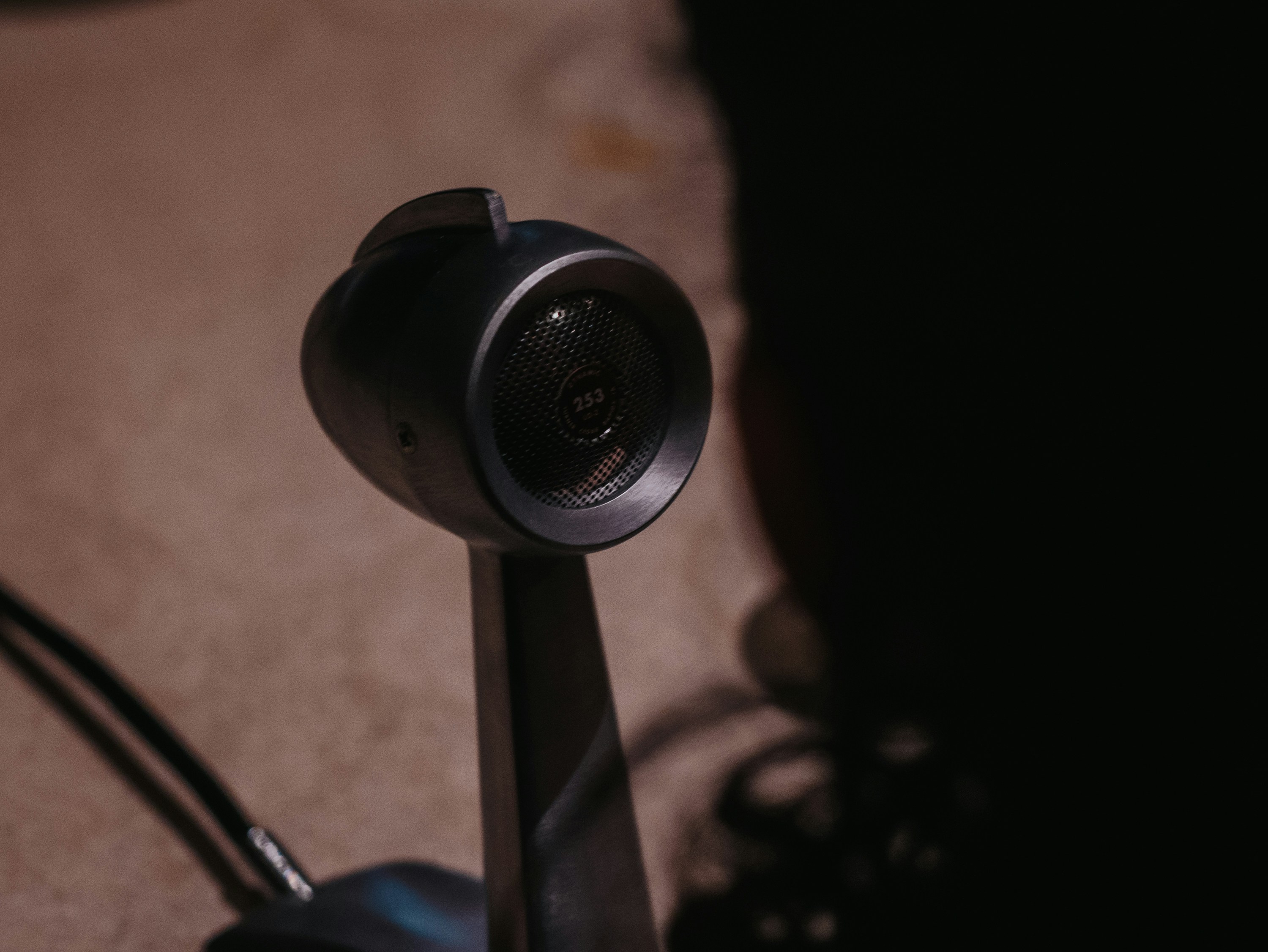 Close-up of a vintage microphone with a person's silhouette.