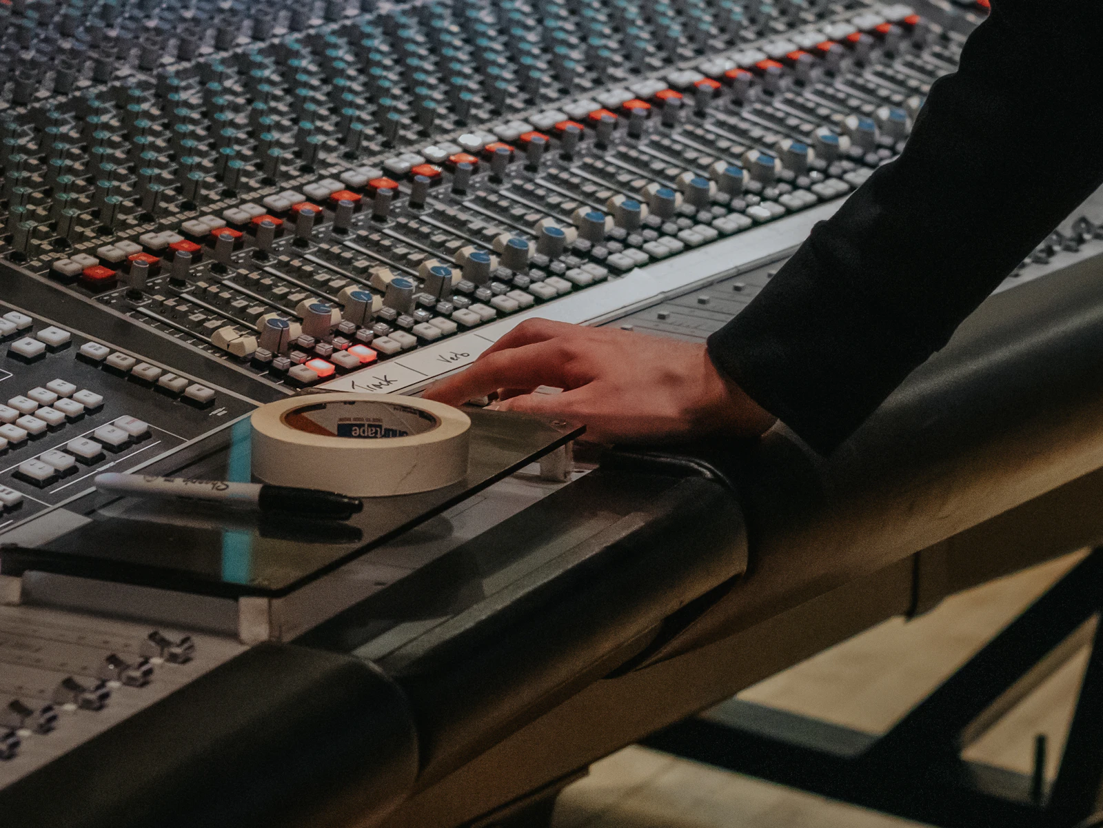 Hand operating an audio mixing console used as representative service imagery