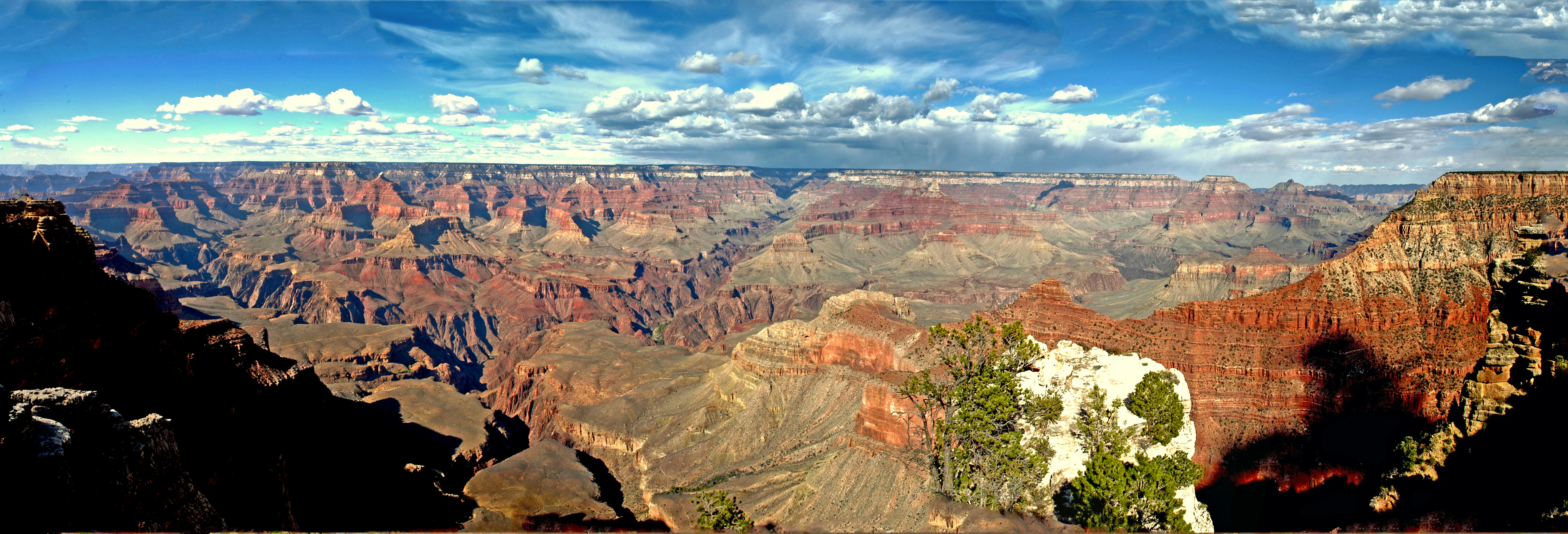 Vast canyon landscape under a blue sky with clouds.