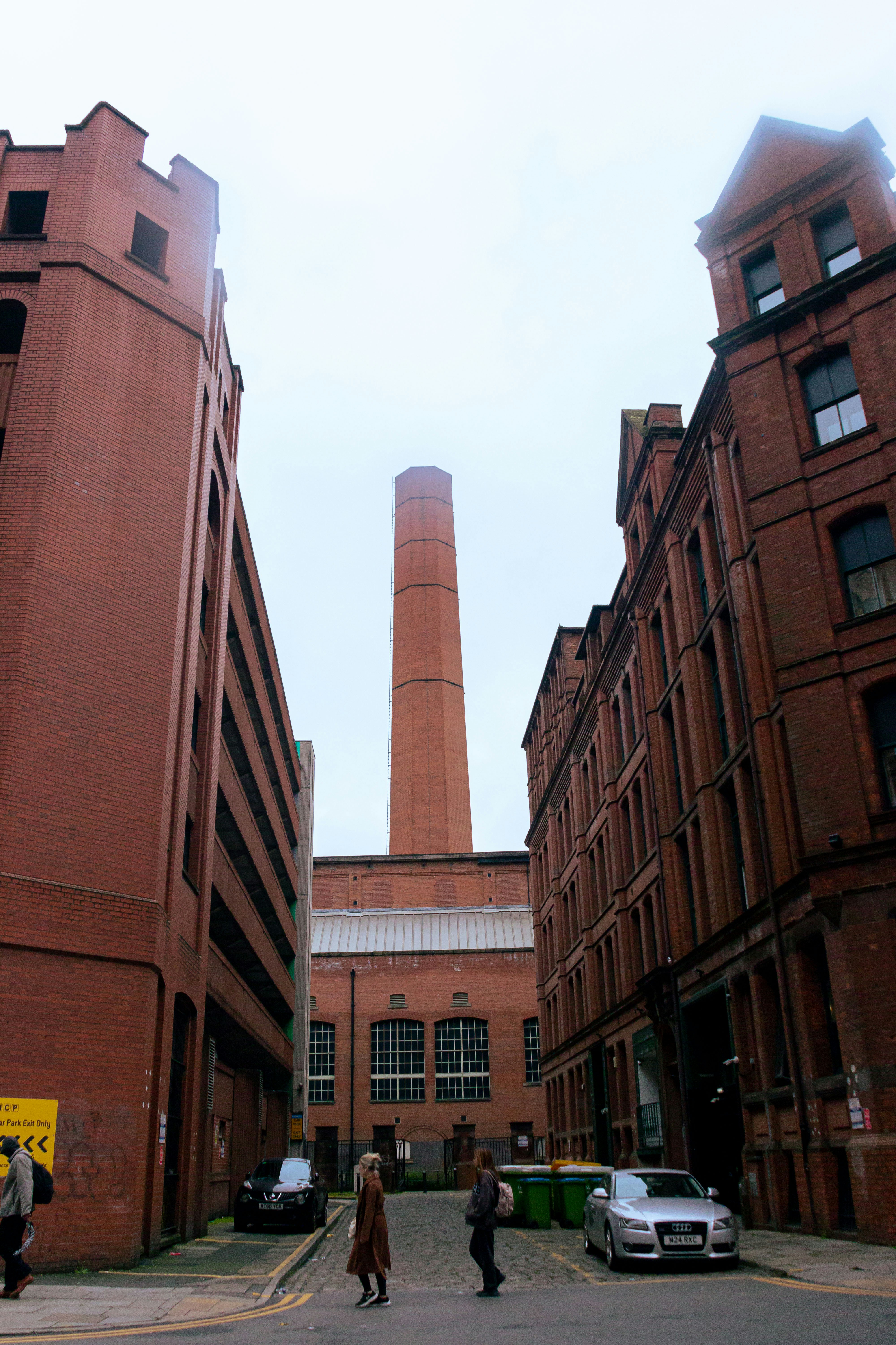 Alta chimenea de ladrillo que se eleva entre antiguos edificios industriales
