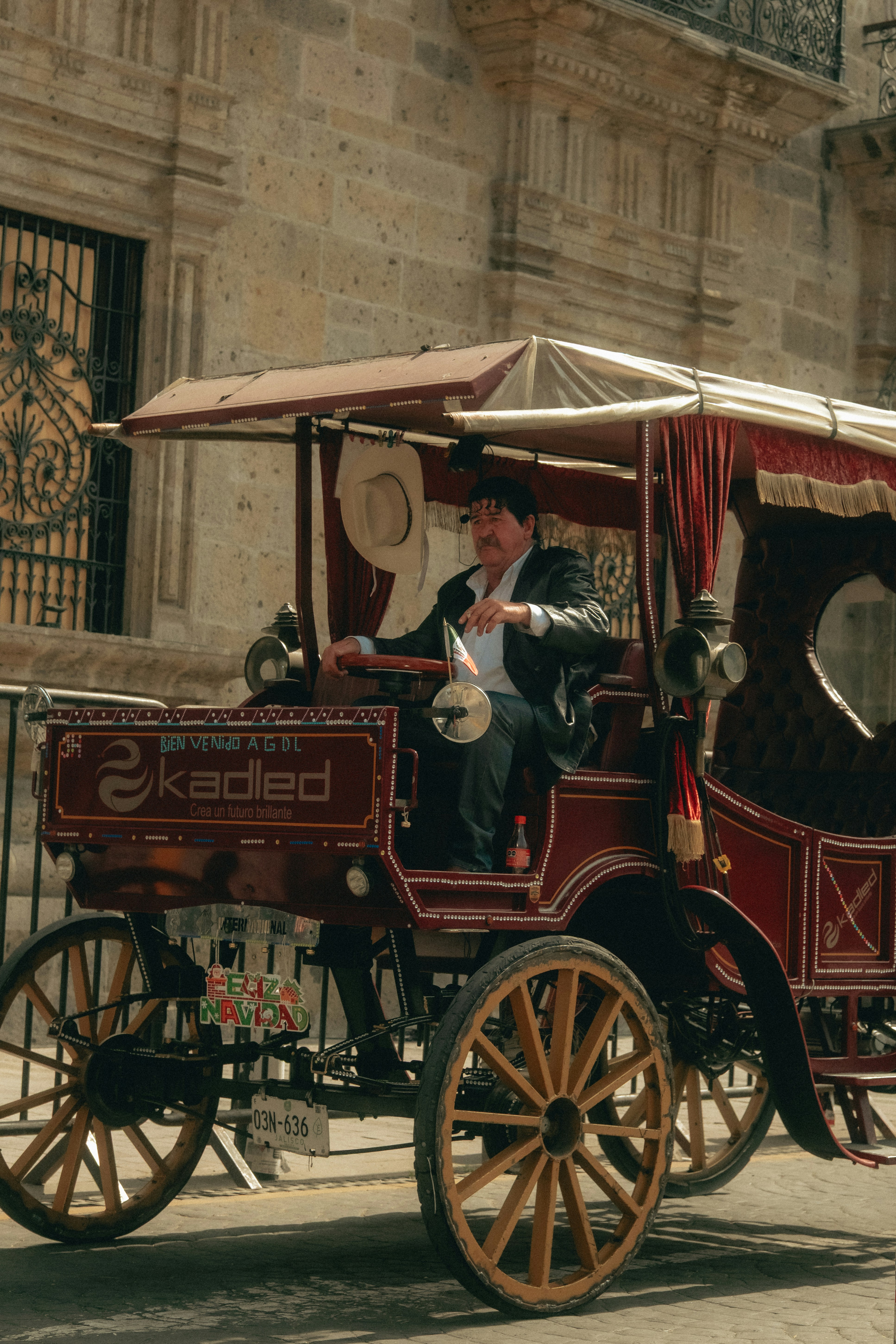Man driving a horse-drawn carriage in a city.