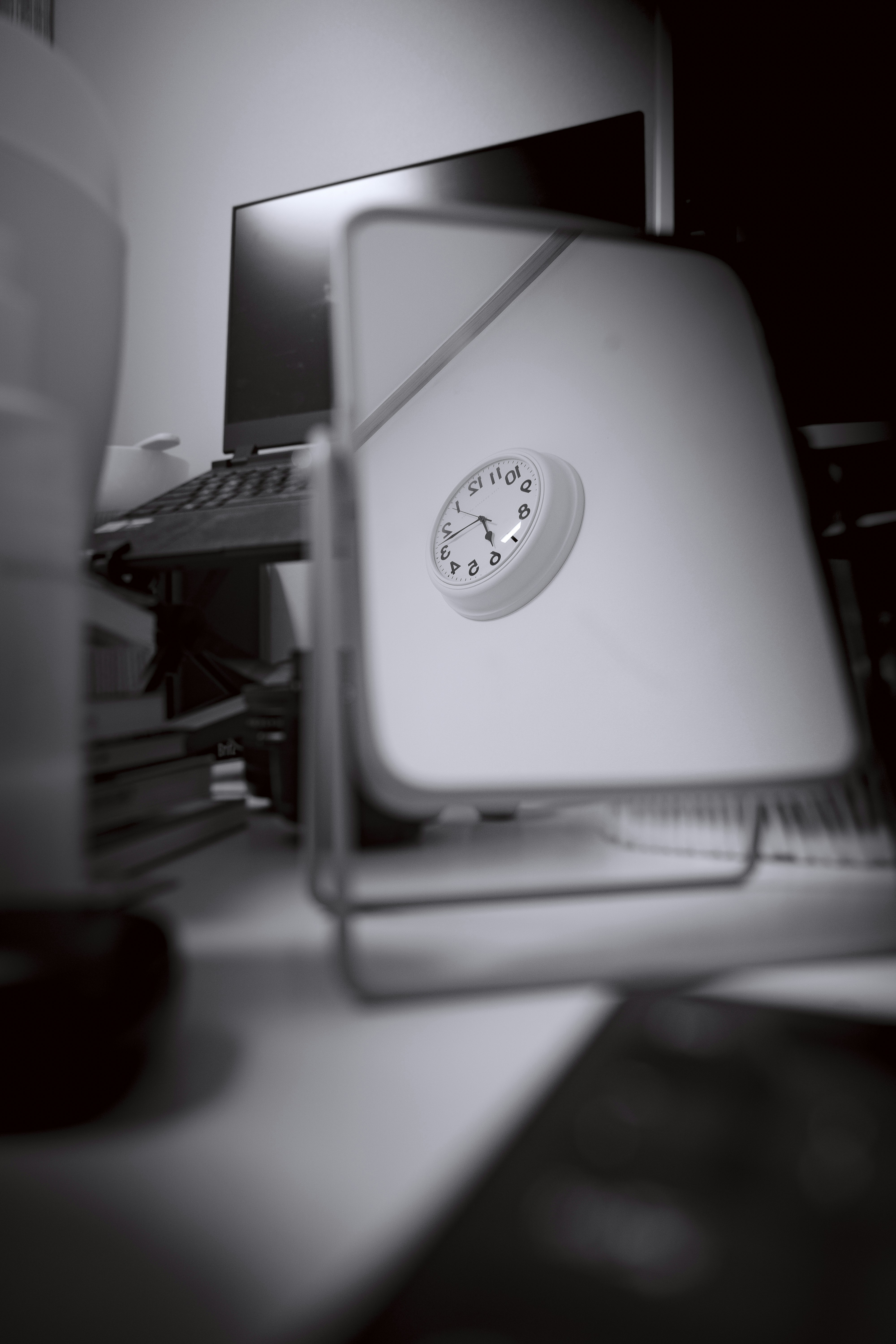 A clock reflected in a mirror on a desk.