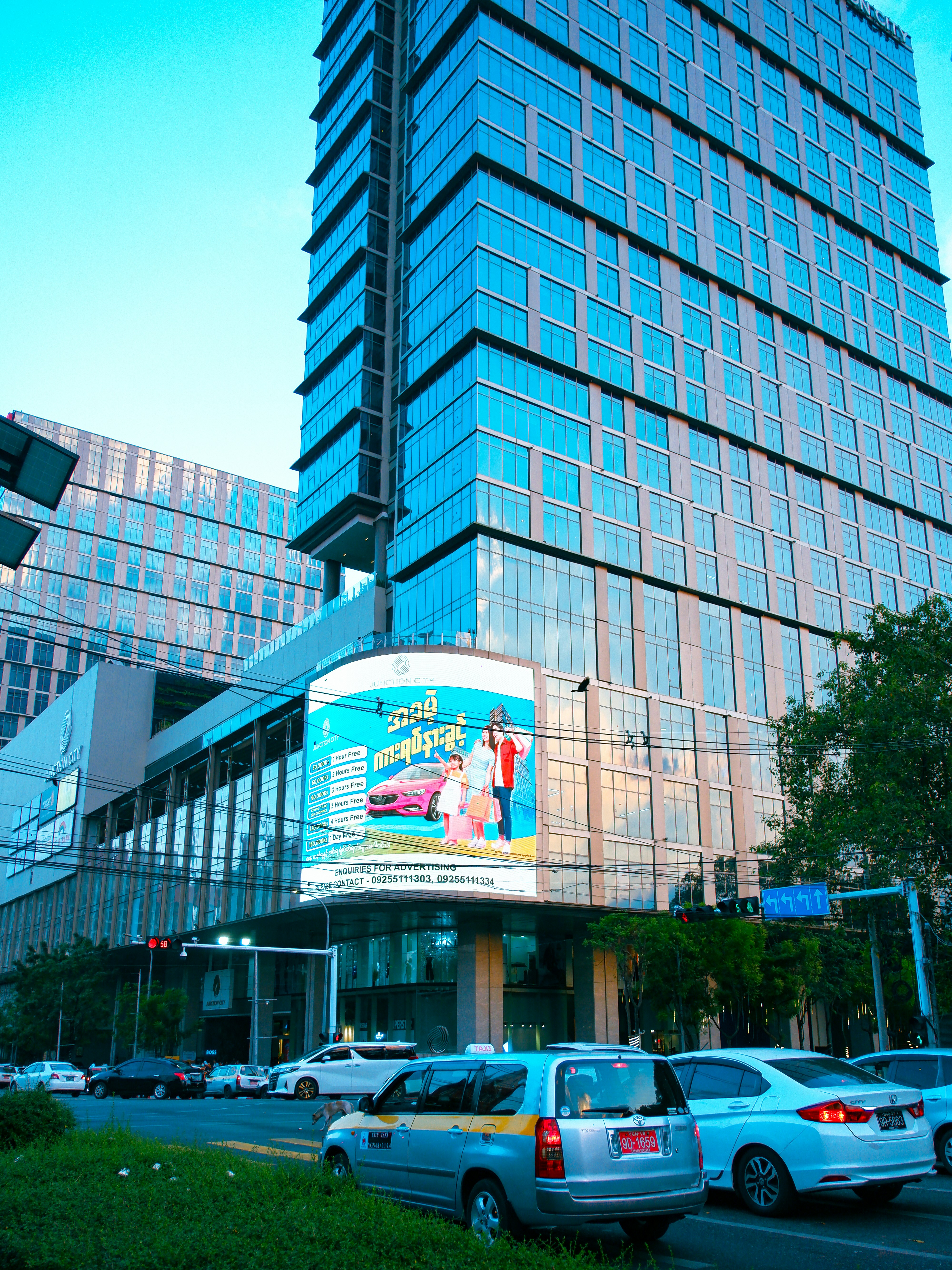 Modern glass skyscraper with a large digital billboard.