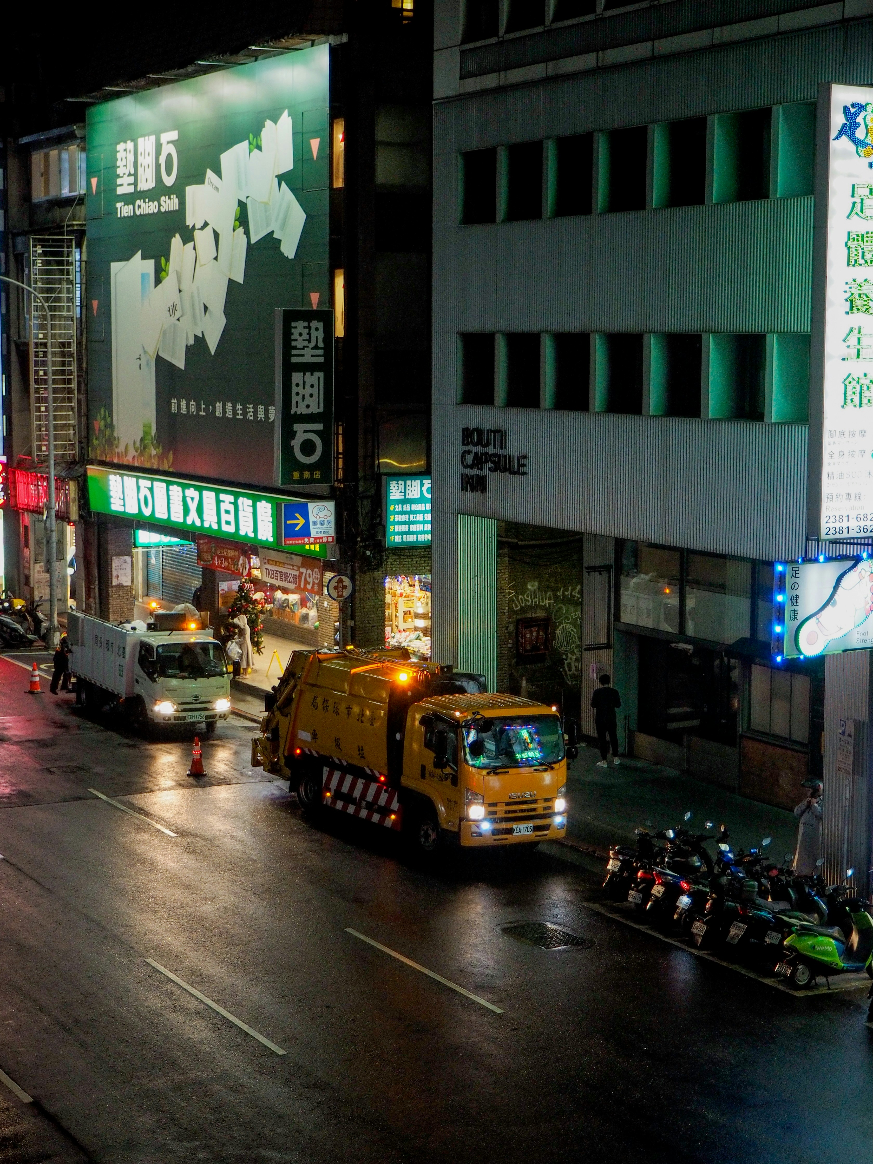 Garbage truck and utility vehicle on wet city street
