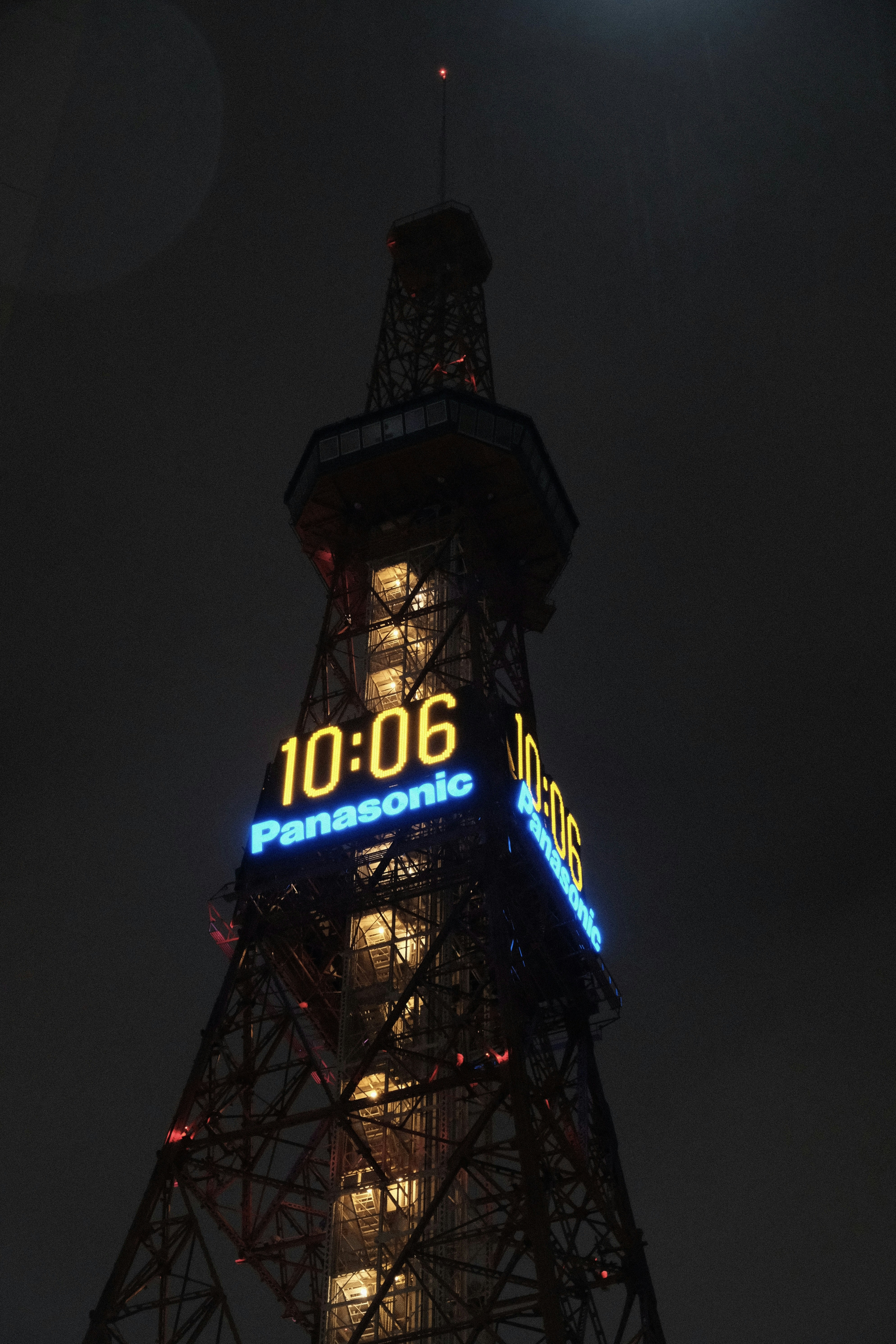 A tall tower with a digital clock at night.