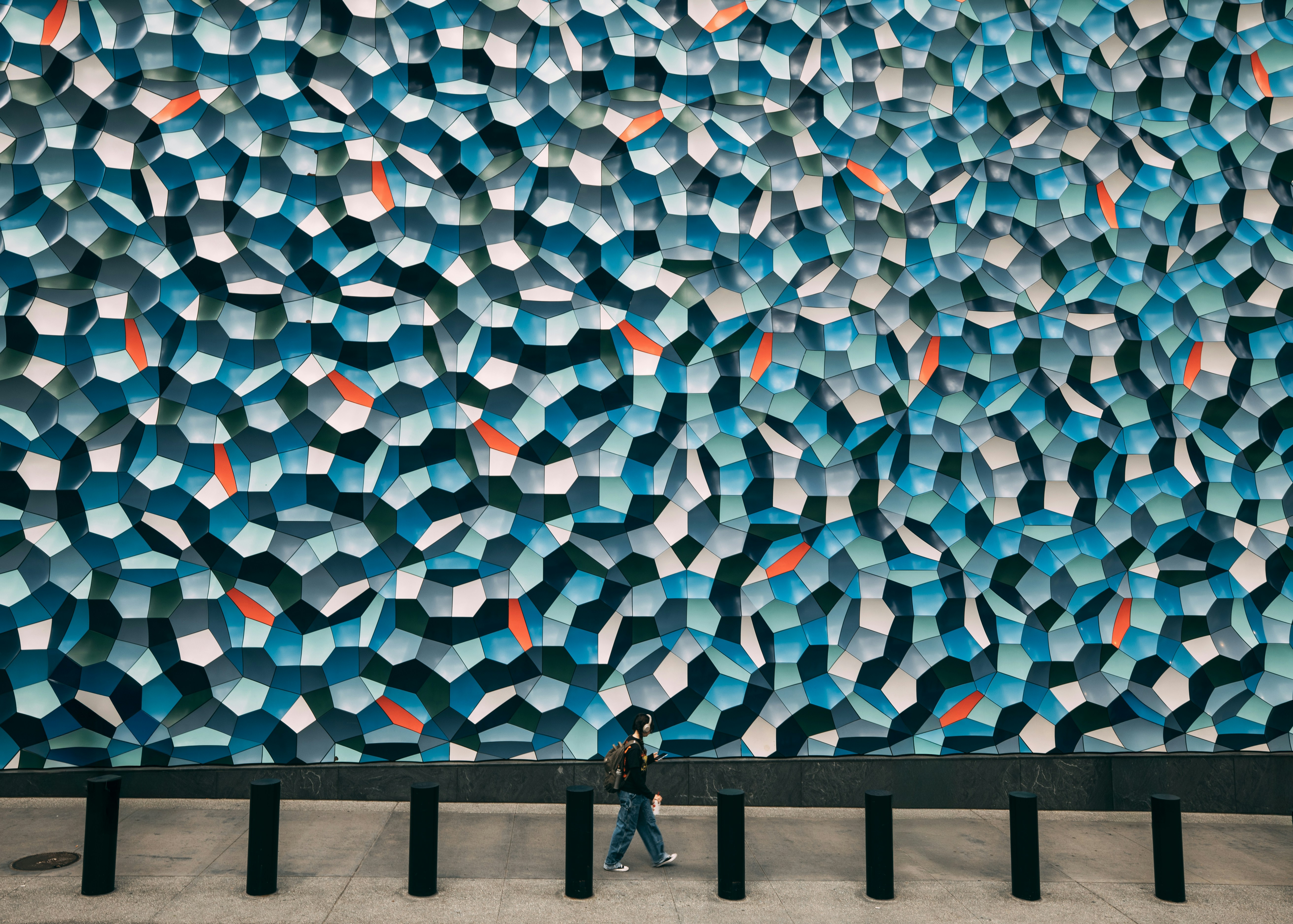Person walks past a large abstract blue patterned wall.