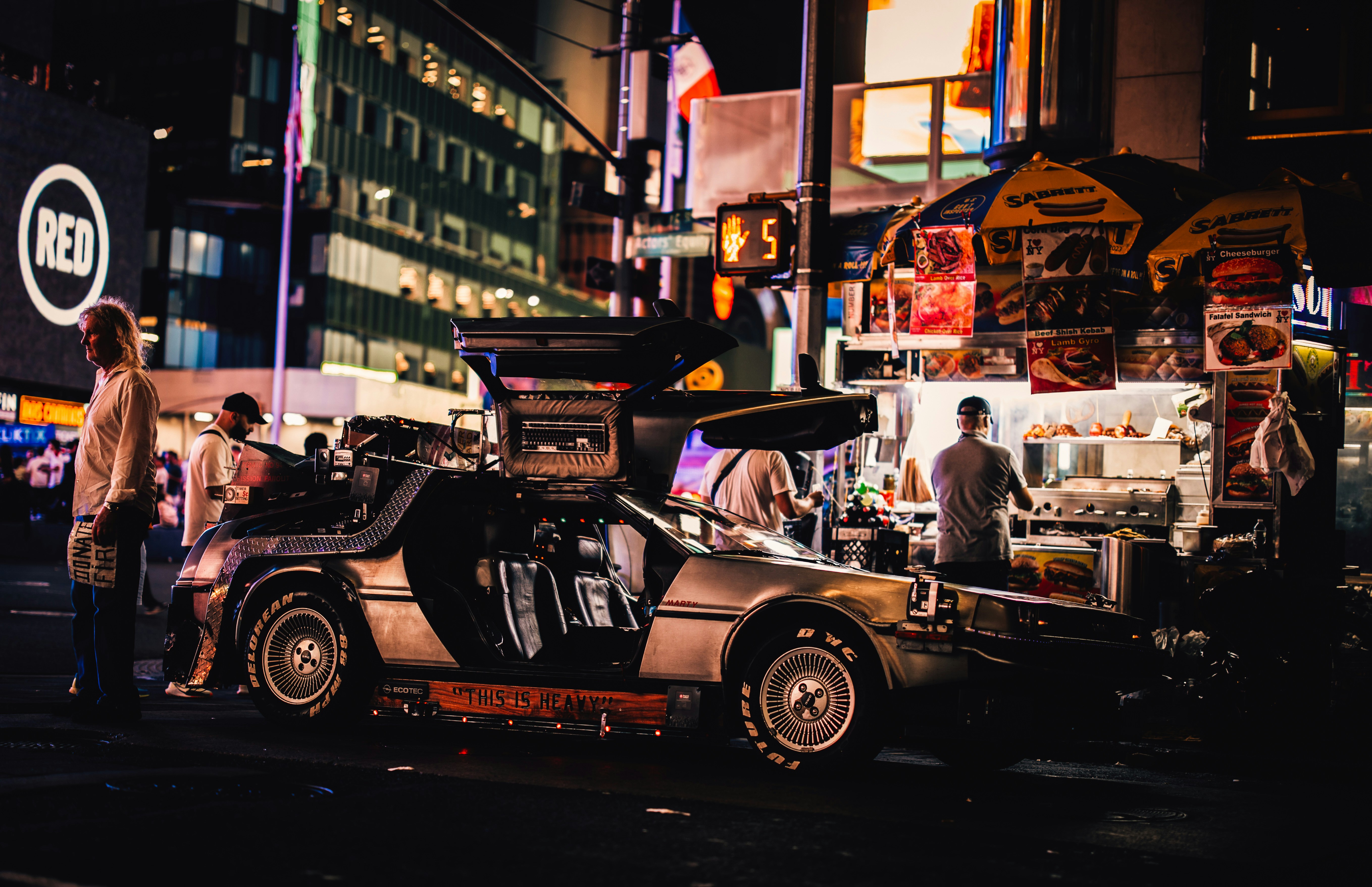 Retro car parked near food stand at night.