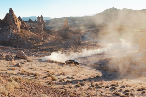 Off-road vehicle kicking up dust in desert landscape