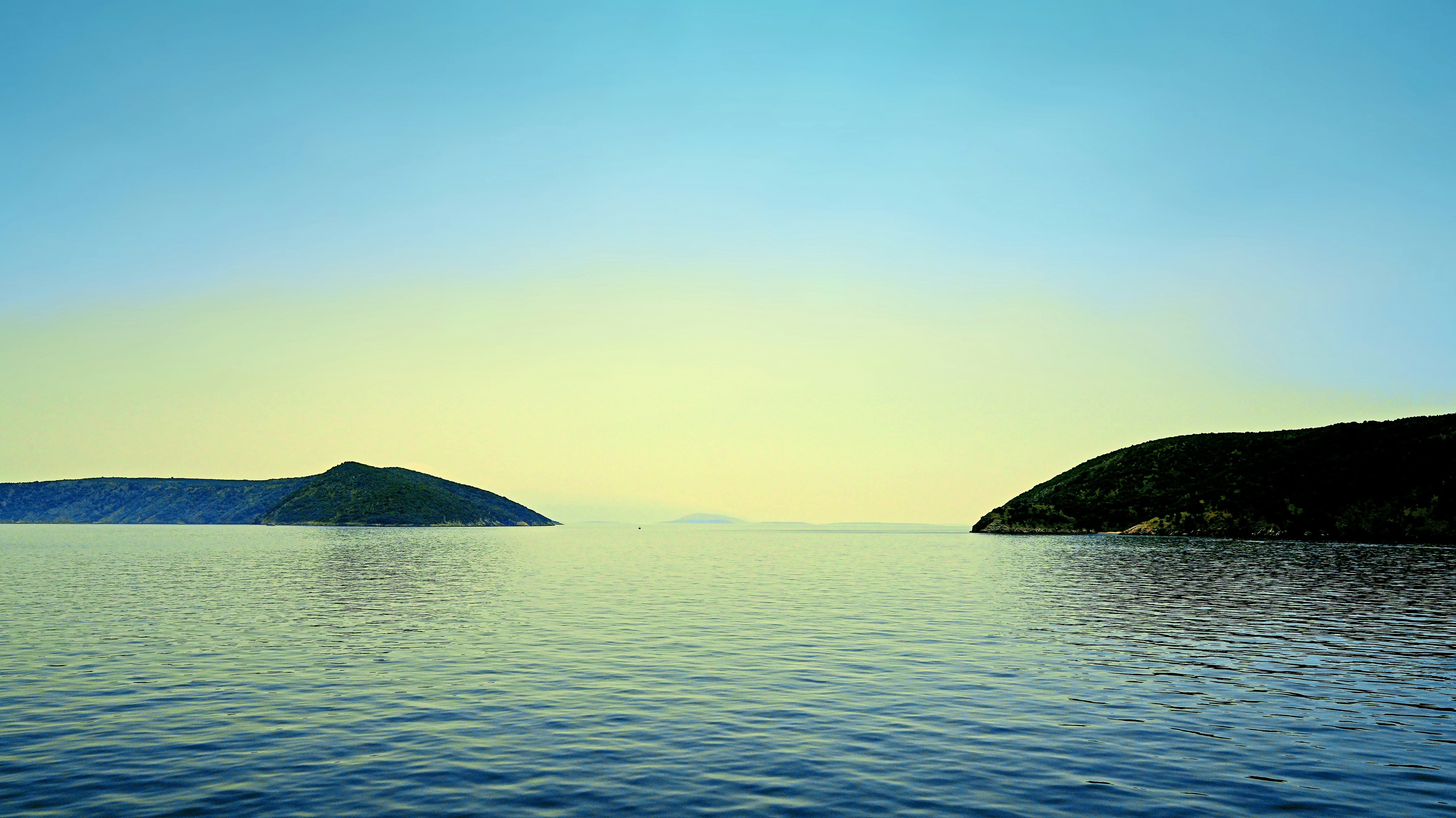 Calm ocean between two islands at sunset