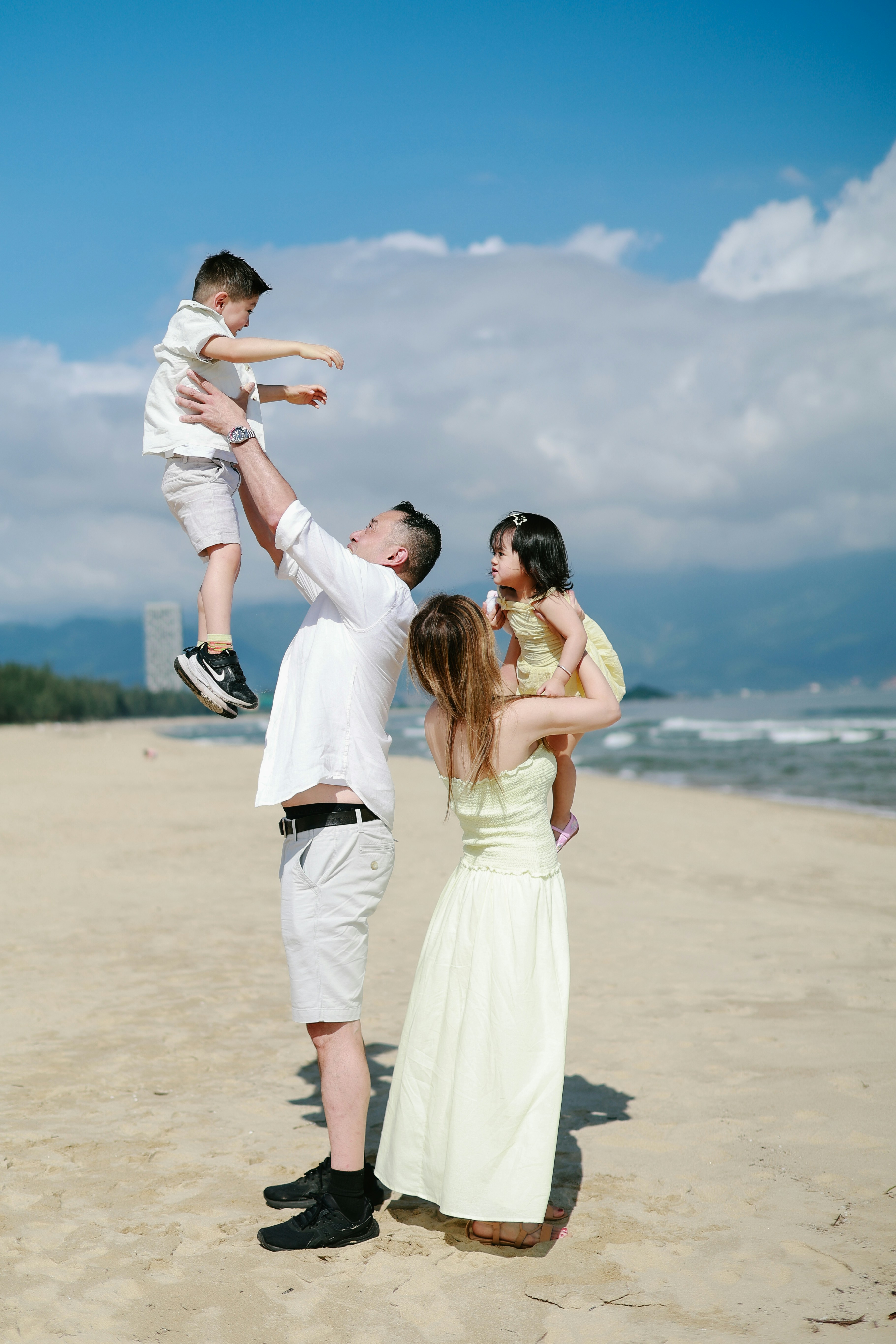 Family playing on a sunny beach with ocean background