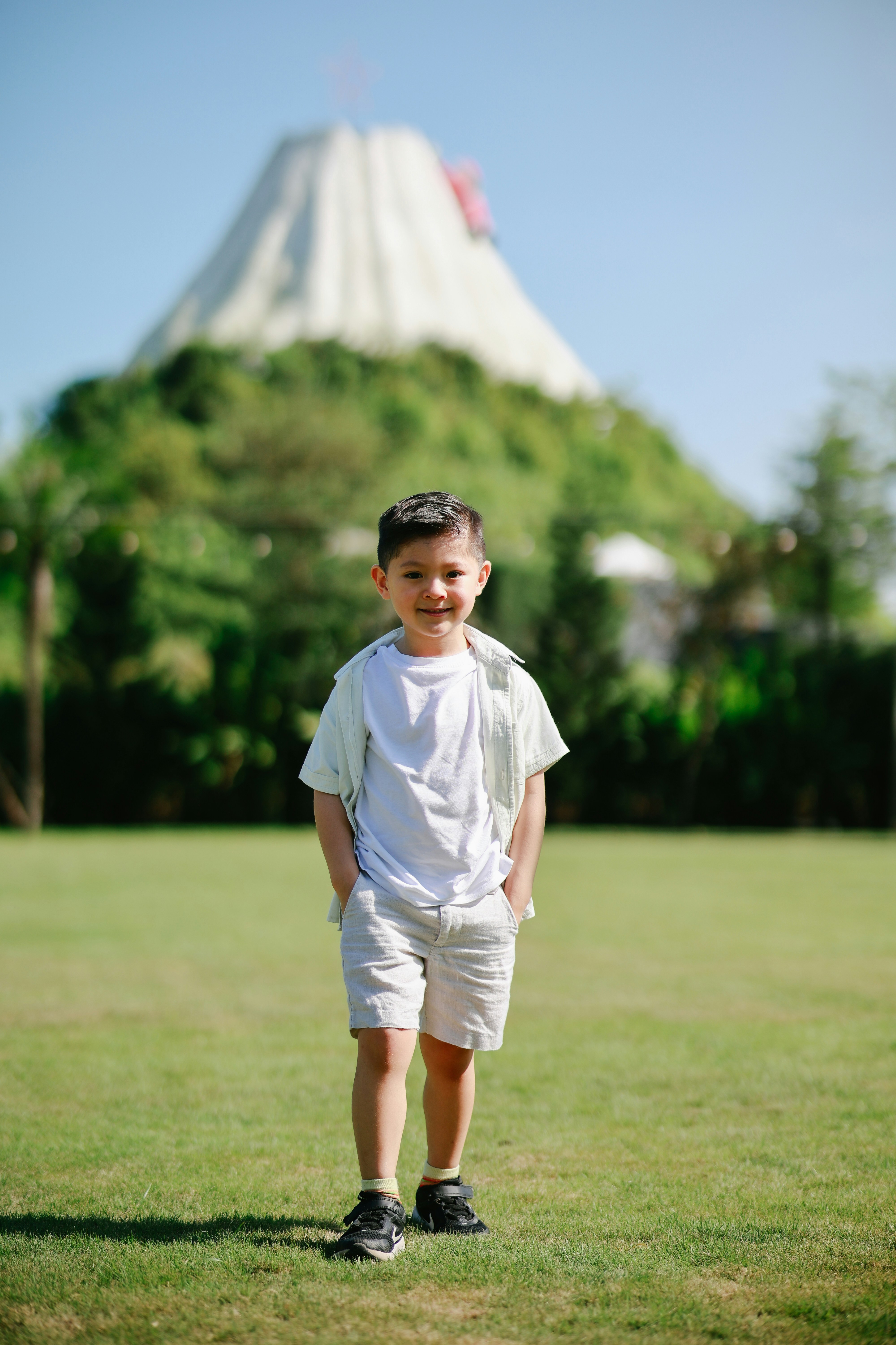 Young boy standing on grass with volcano behind him.