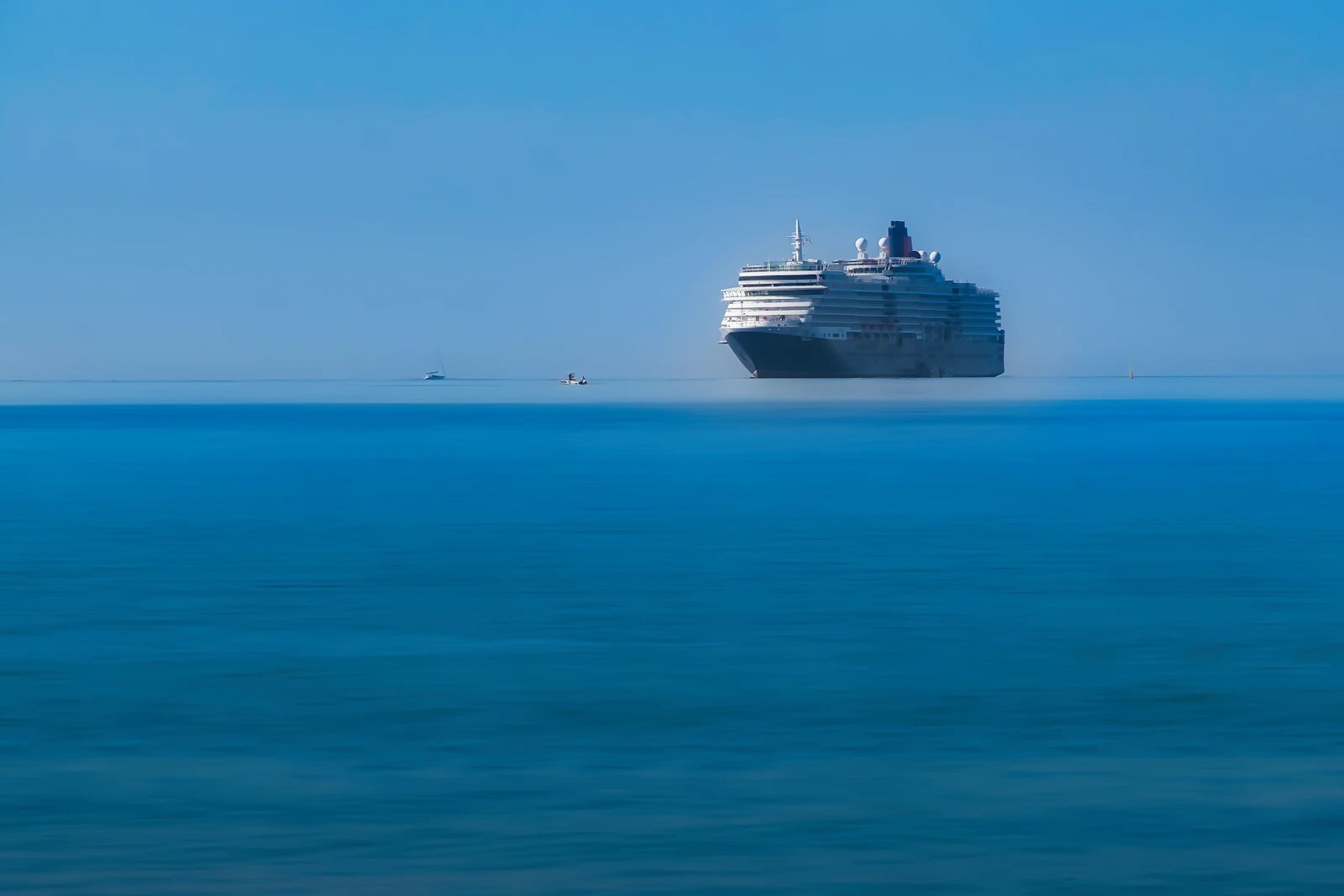 A large ocean cruise liner sailing across calm blue water