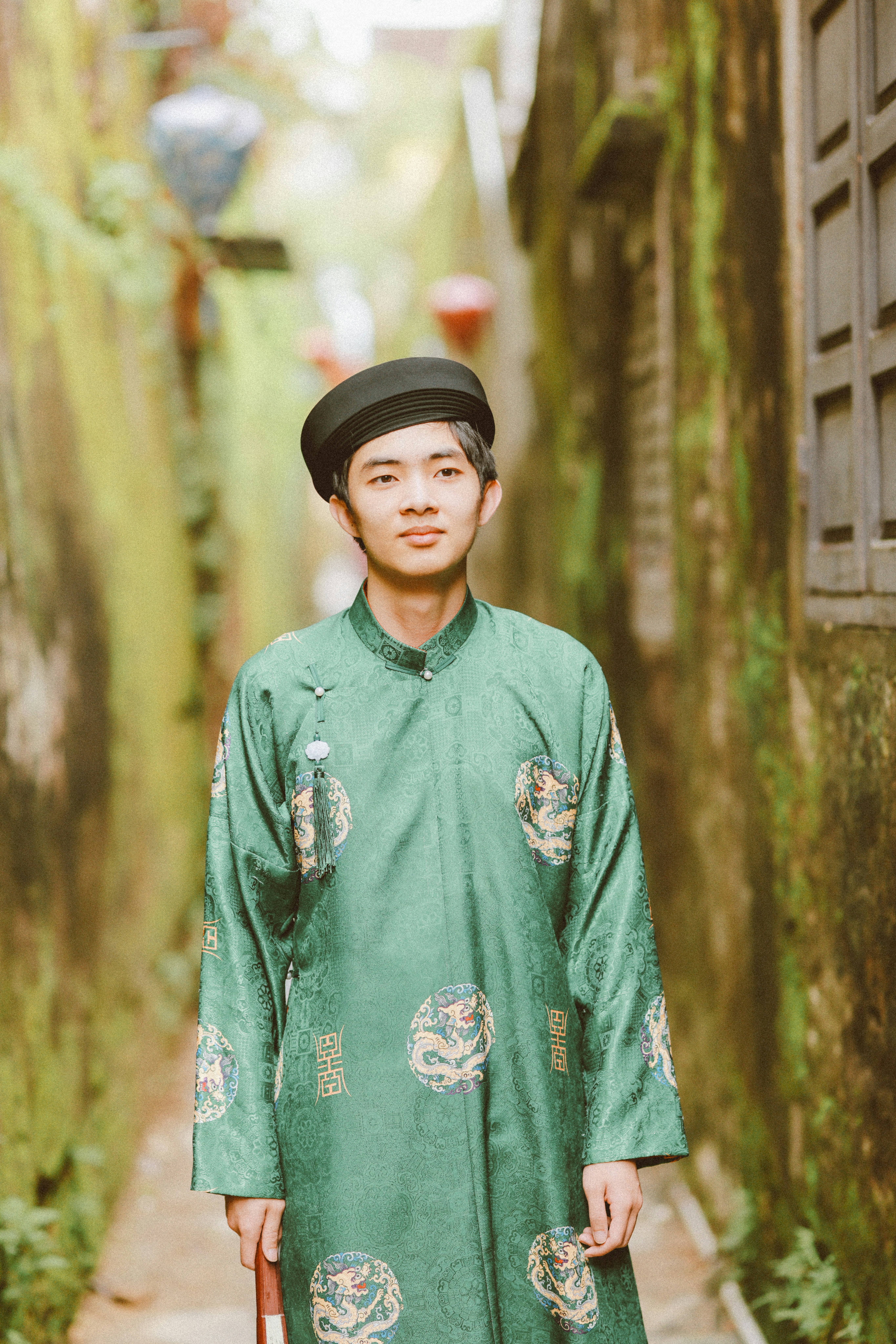 Joven con el típico áo dài verde vietnamita y sombrero.
