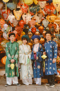 Four people in traditional vietnamese ao dai and hats