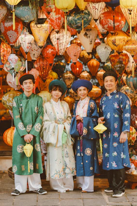 Four people in traditional vietnamese ao dai and hats