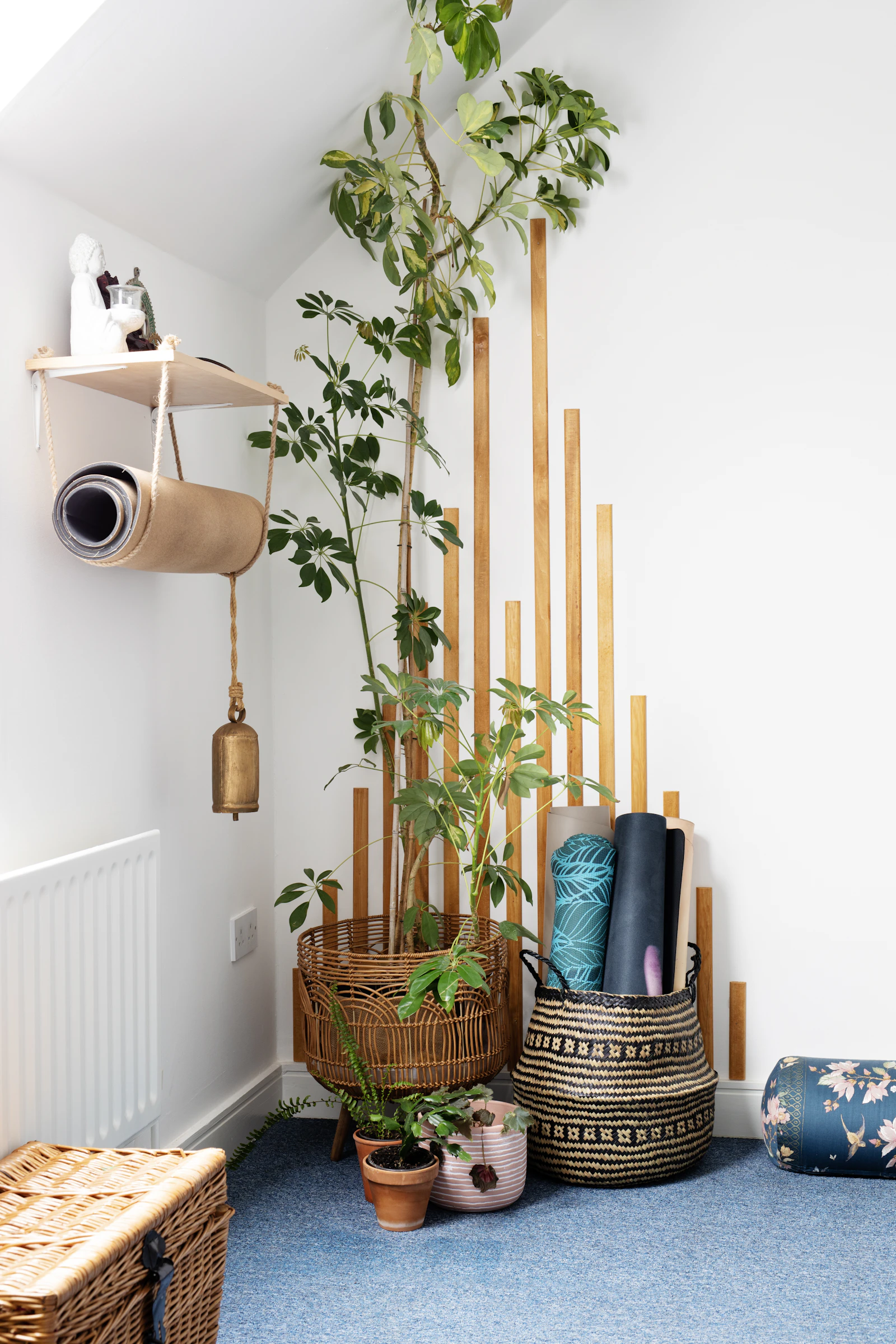 Yoga mats stacked beside plants in a bright practice room