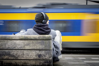 Person with headphones watches a blurred train pass by