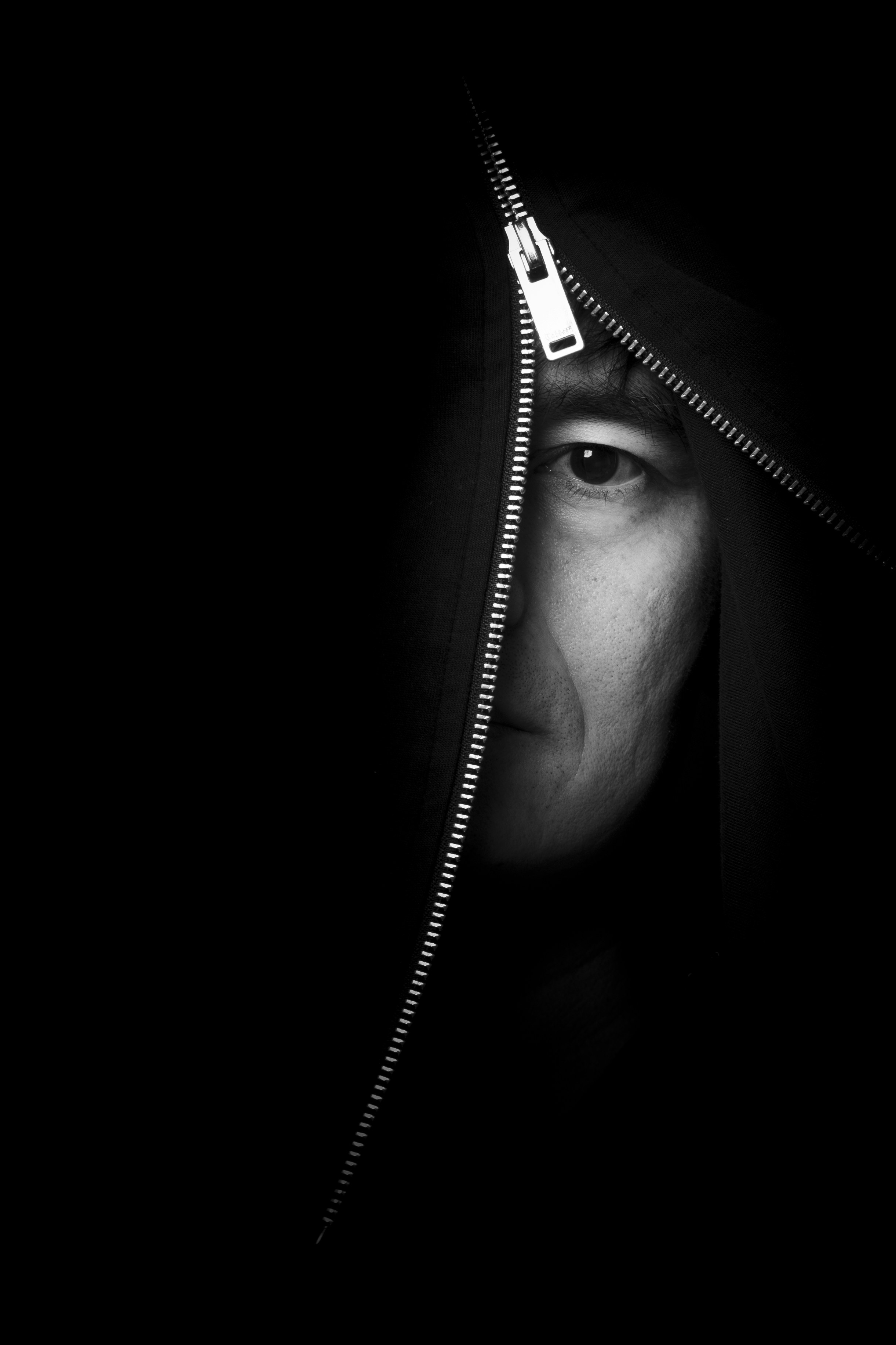 Man's face peeking through a zipper opening.