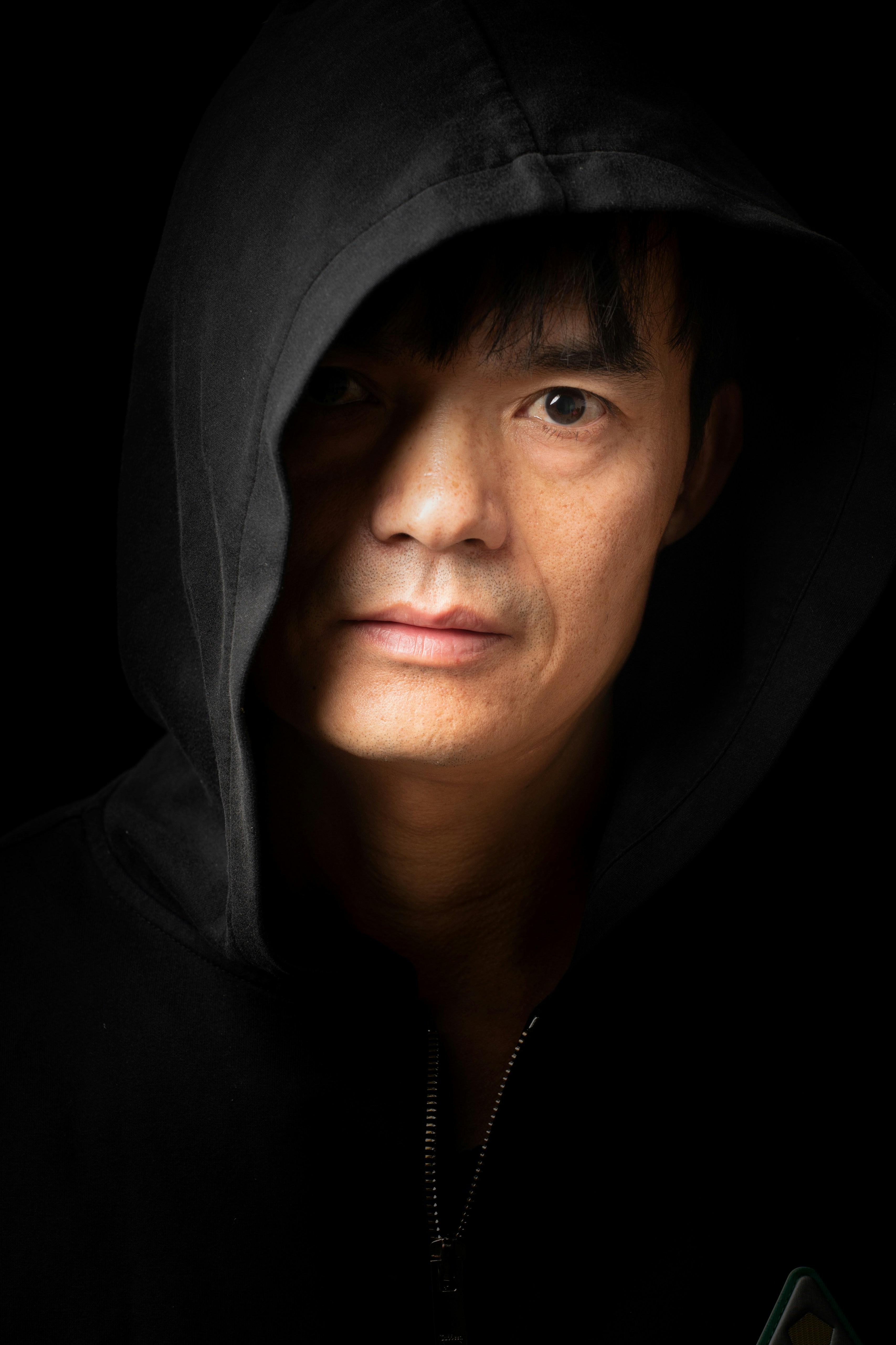 Man with dark hoodie and shadows on face