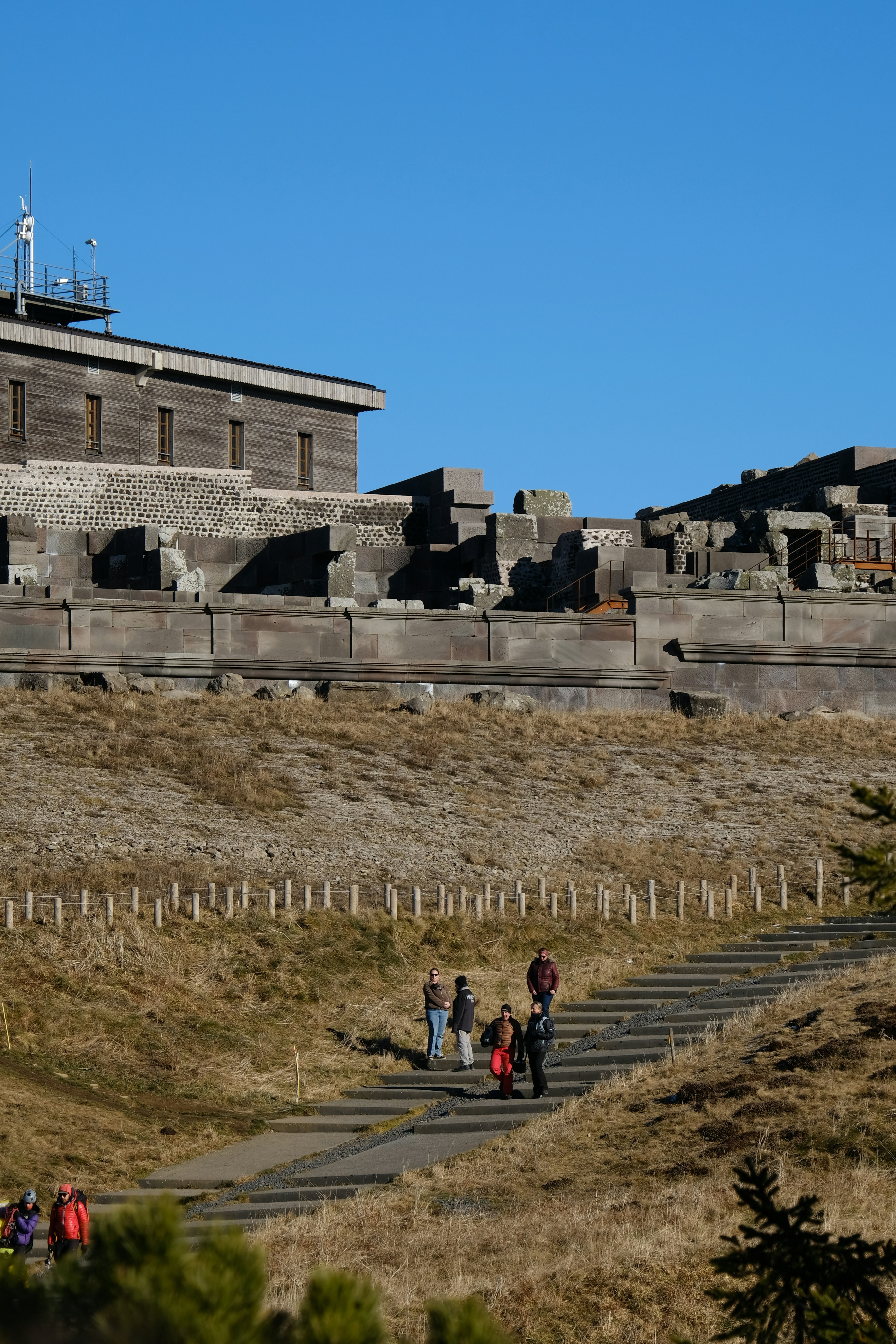 Pessoas caminhando por um caminho em direção a uma grande estrutura de pedra.
