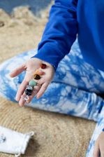 Hand holding colorful chakra healing stones on a mat.