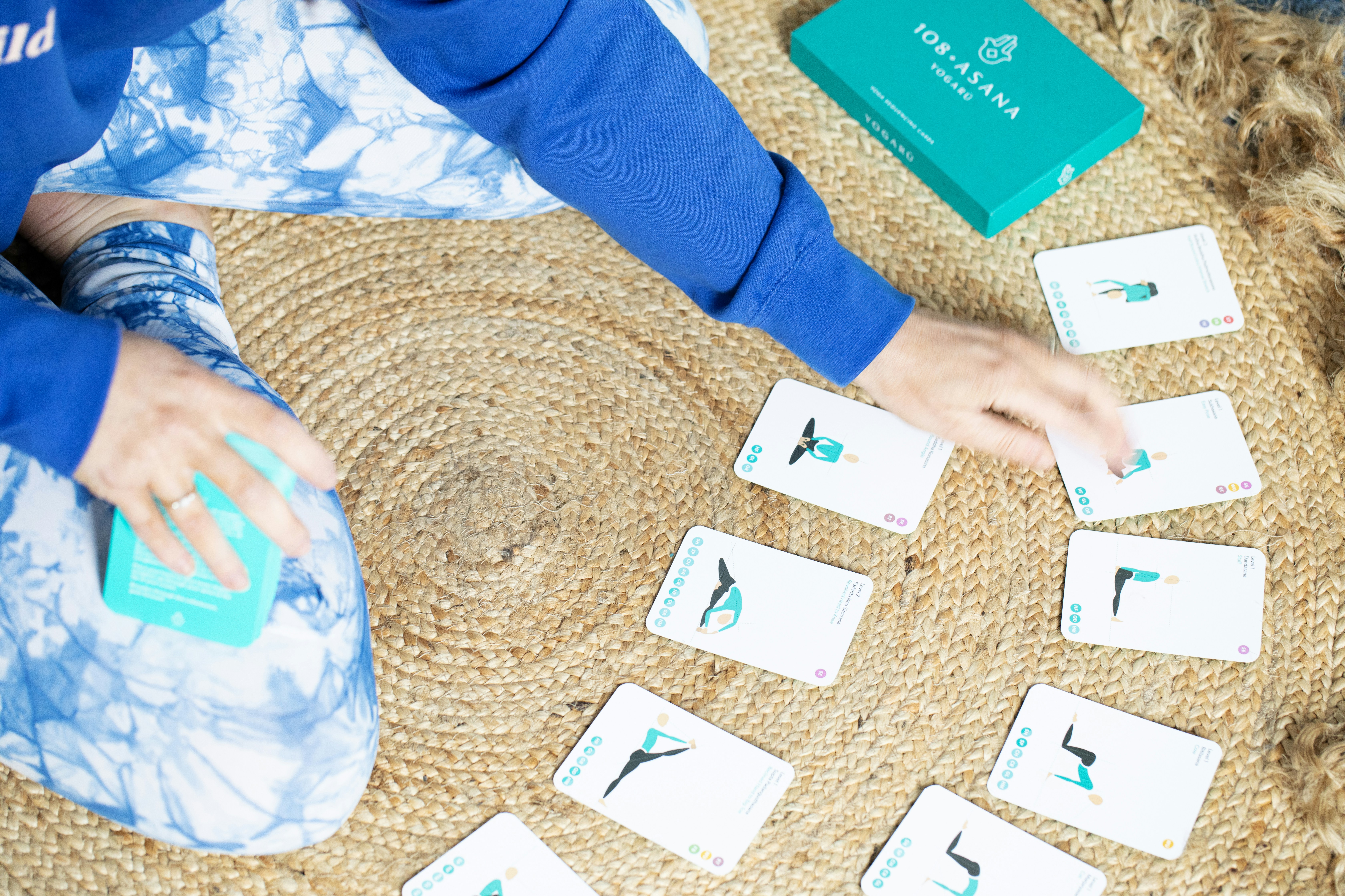 Person arranging yoga pose cards on a rug
