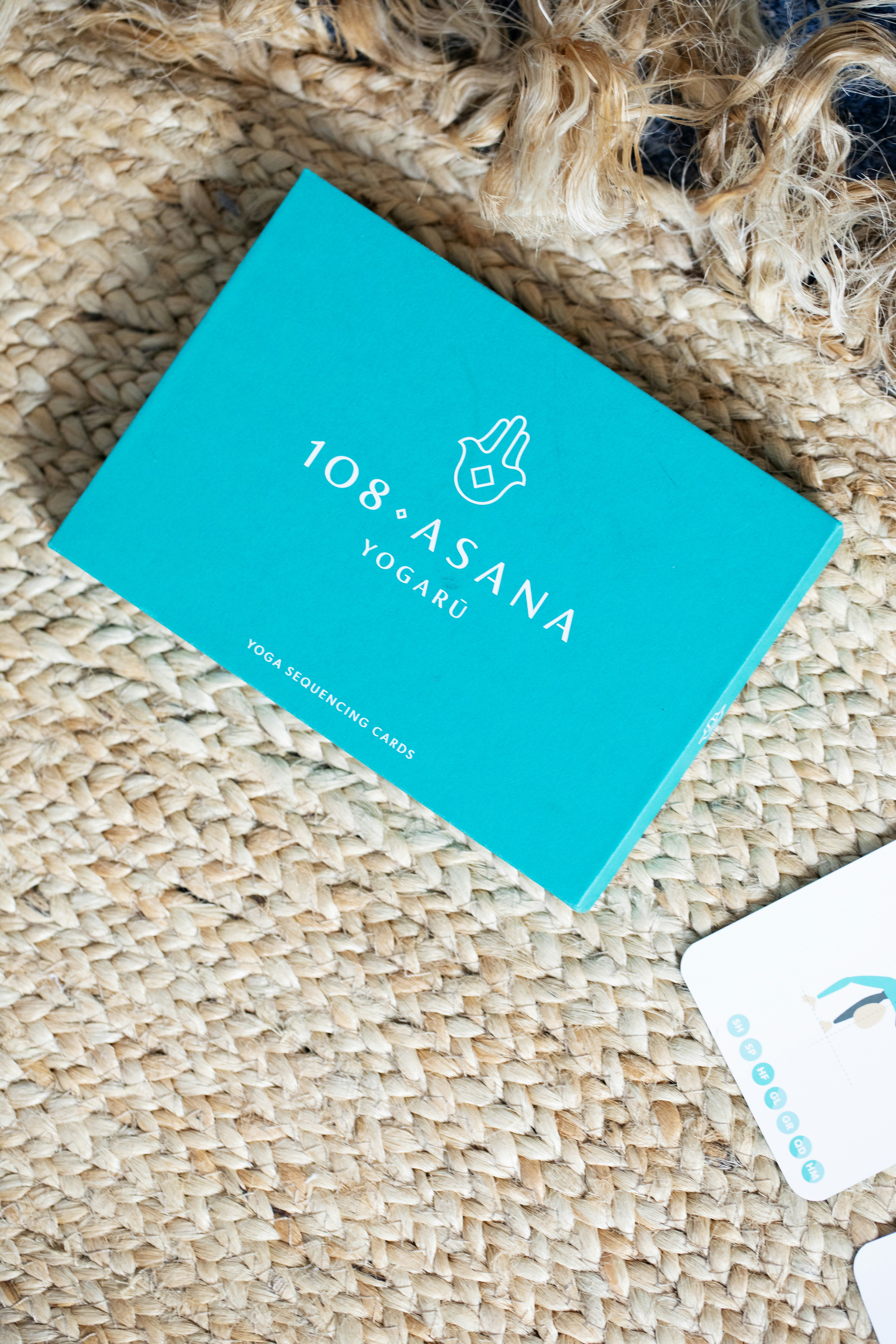 Turquoise yoga cards on a woven mat.
