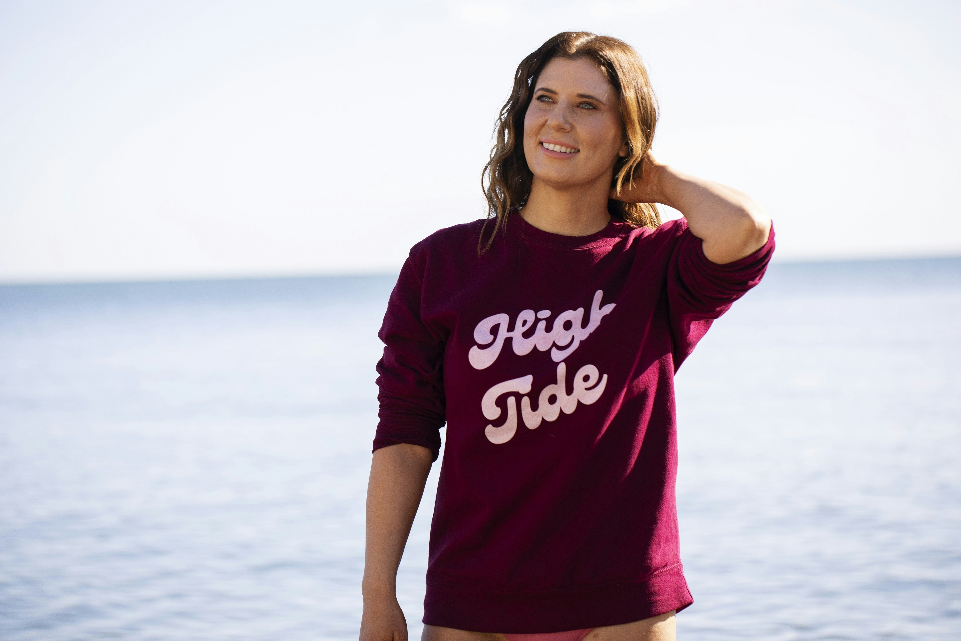 Donna con felpa bordeaux vicino all'oceano