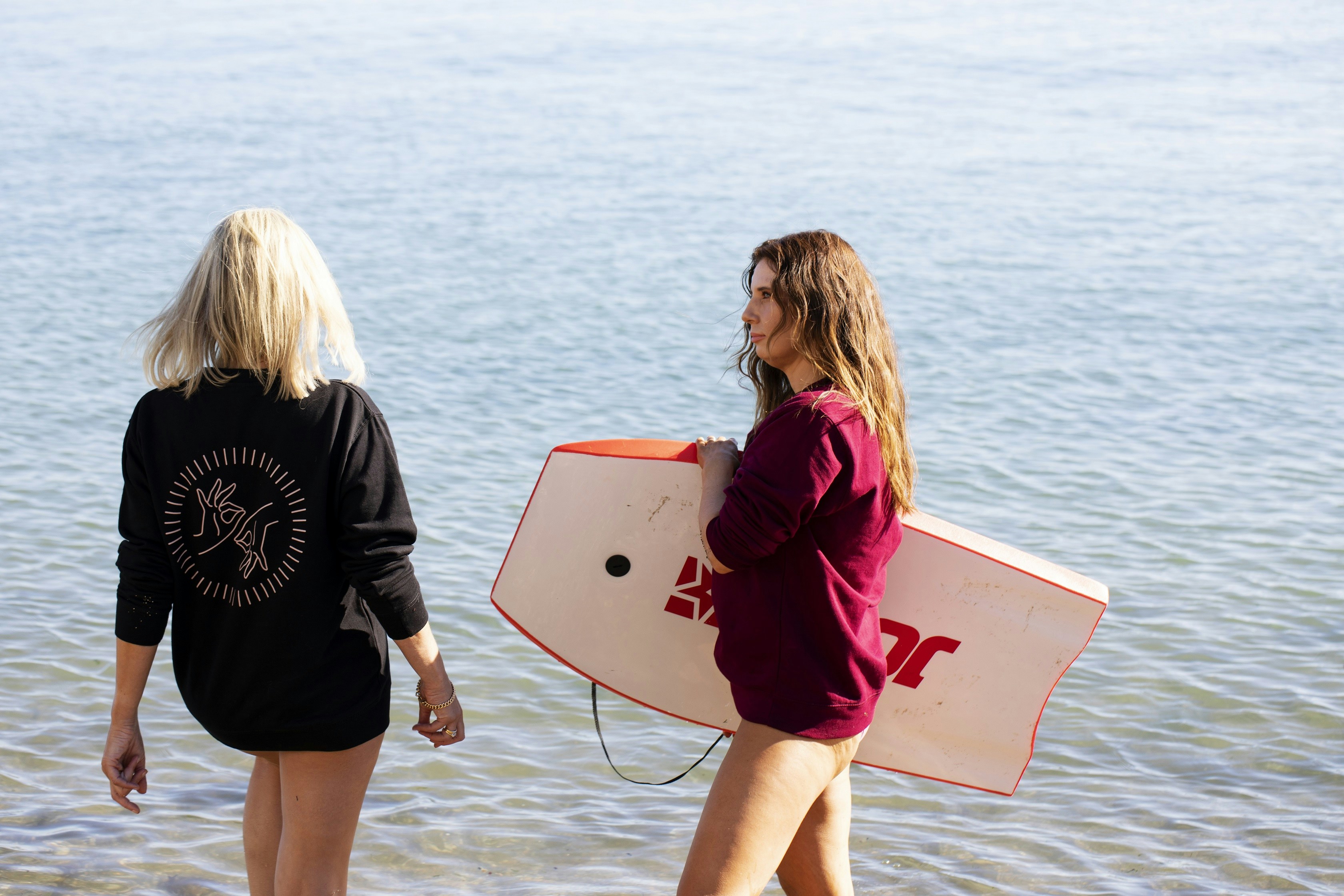 Two women with a boogie board at the beach