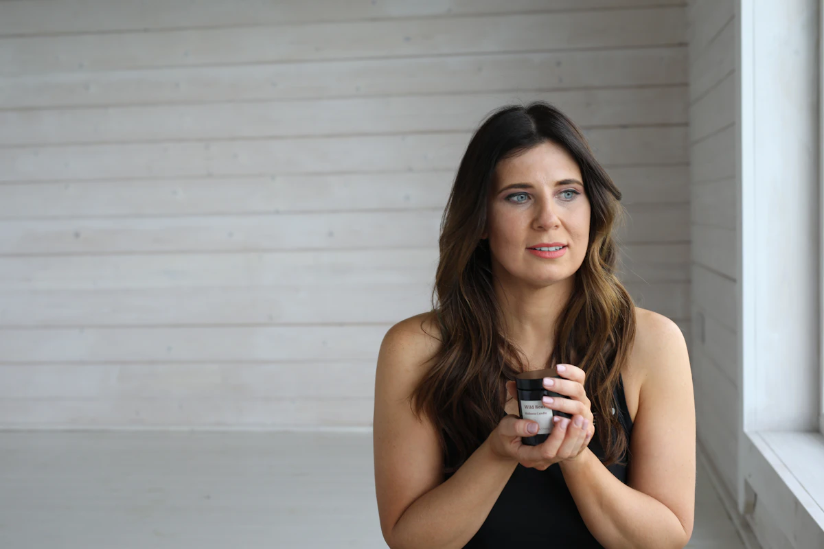 Woman holding a small bottle near a window