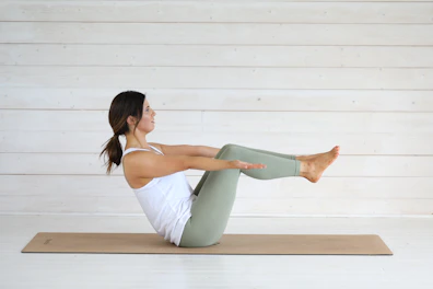 Woman doing yoga boat pose on mat