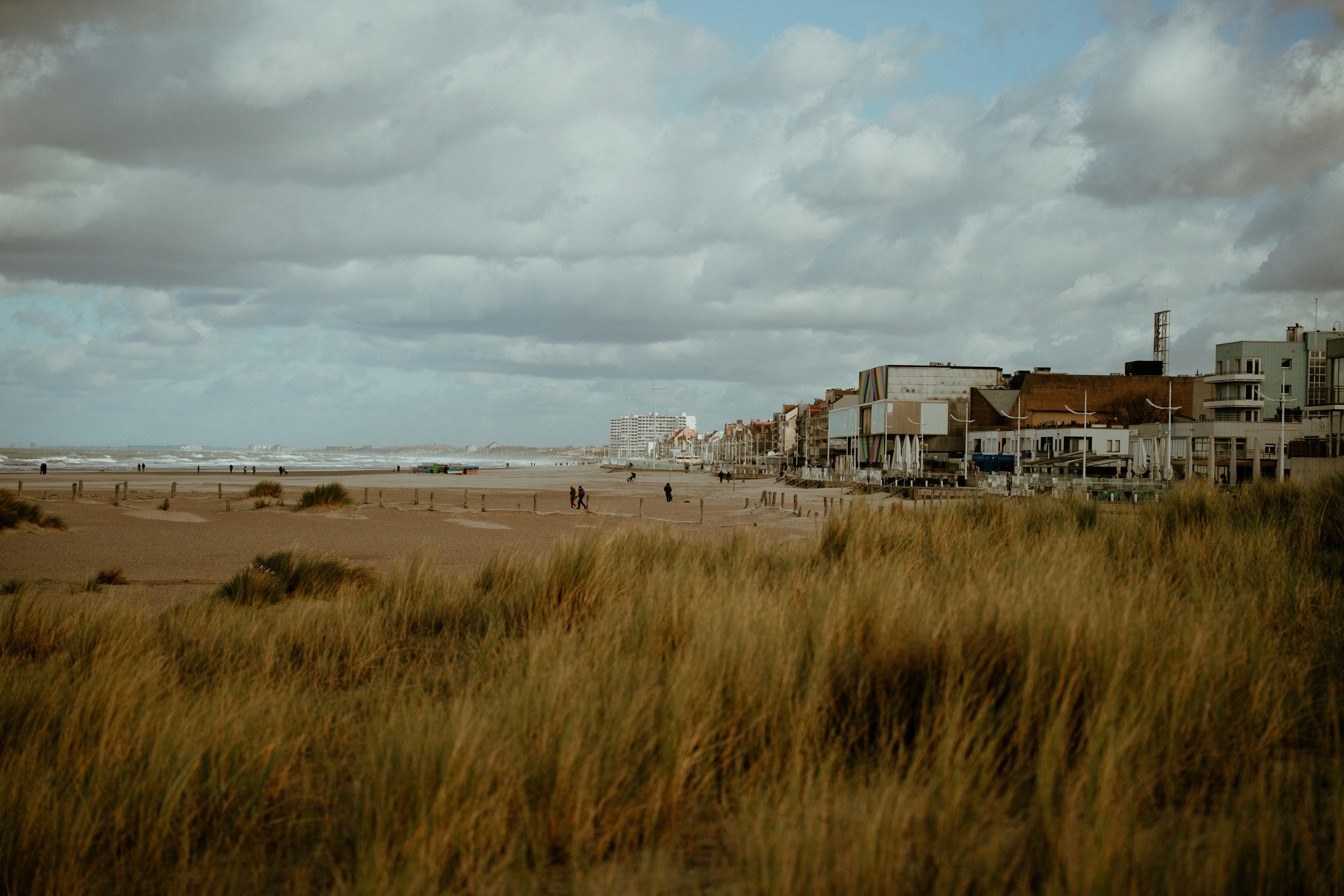 Cidade litorânea com dunas gramadas e céu nublado