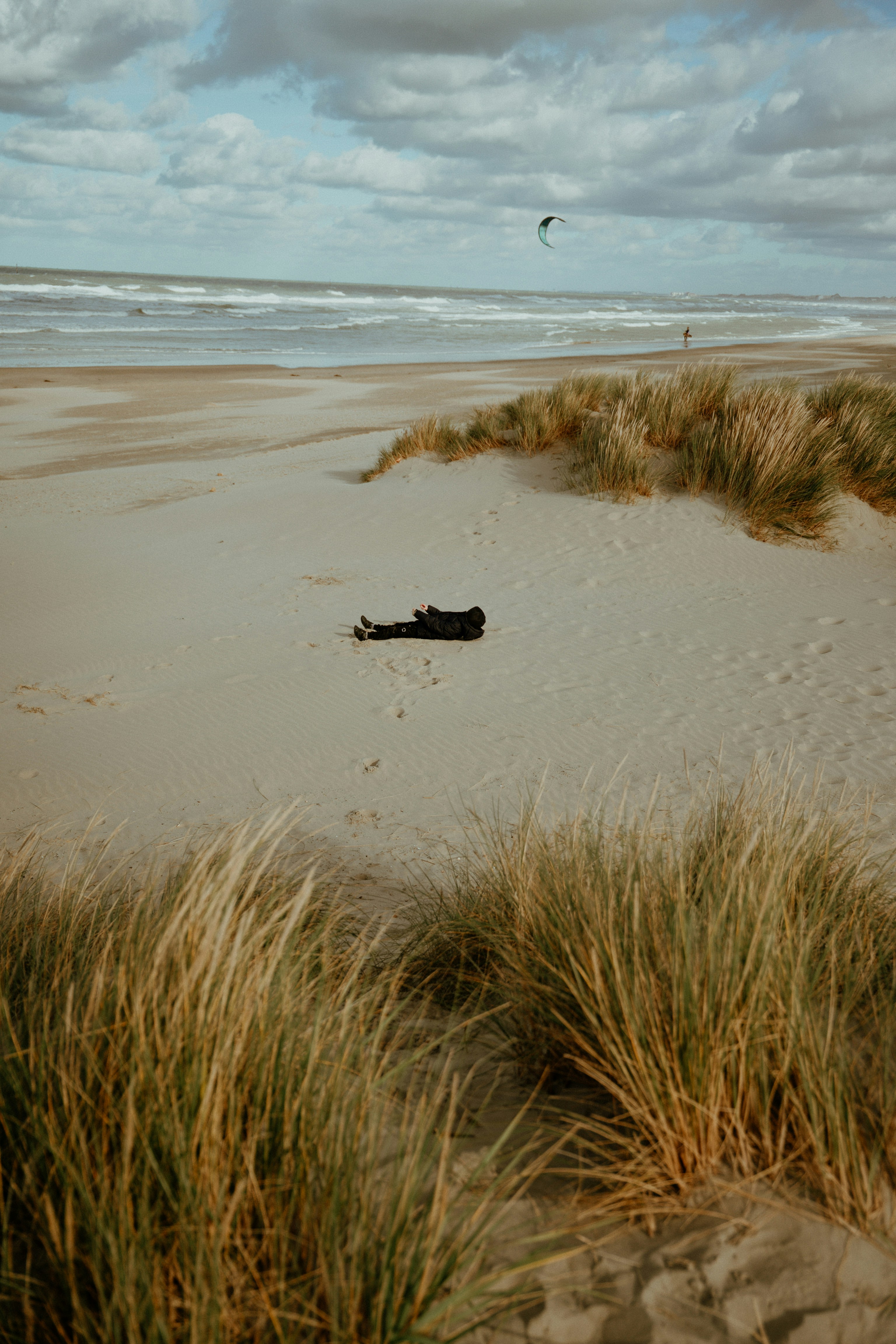 Pessoa deitada em dunas de areia perto do oceano