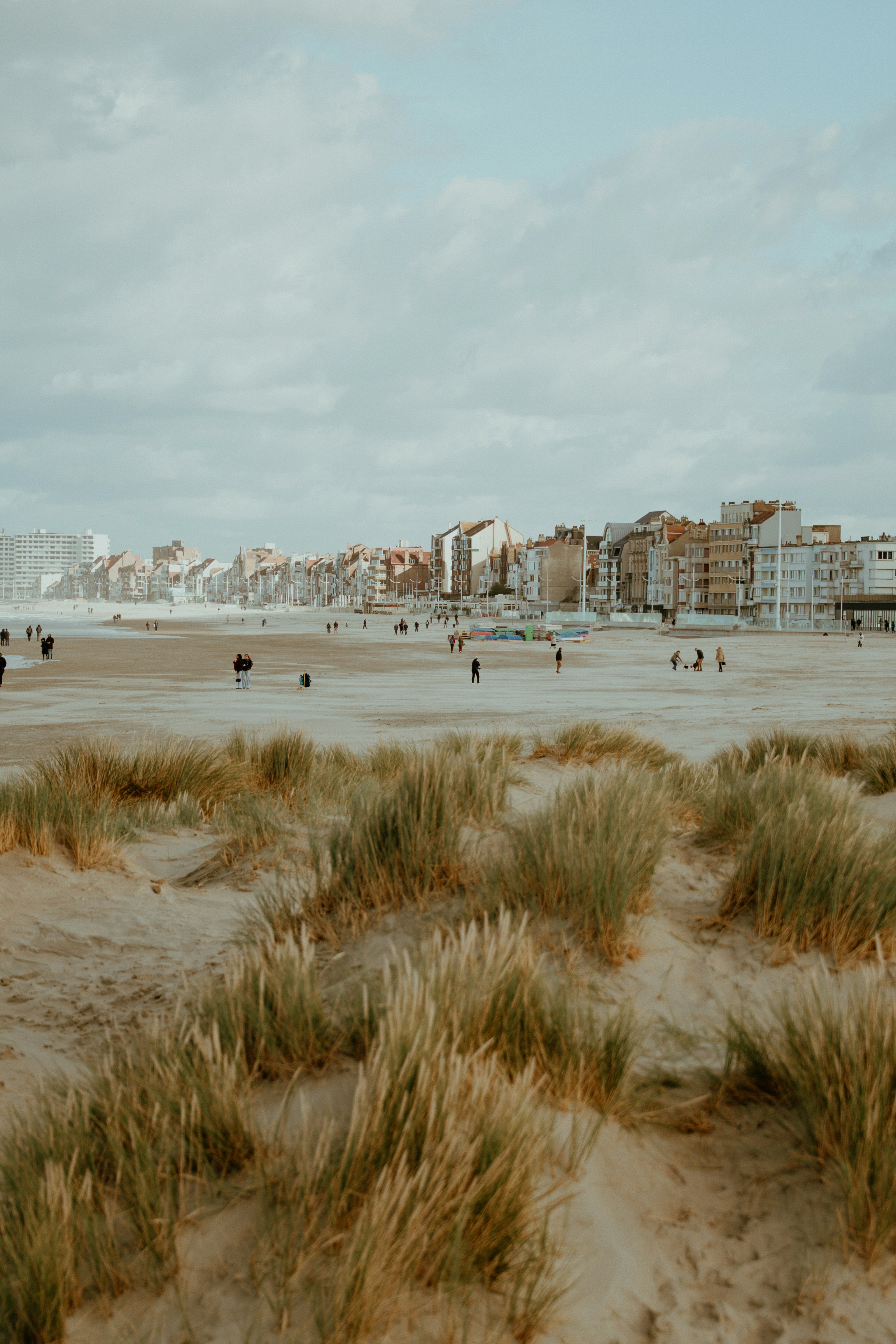 Dunas de praia de areia com prédios e pessoas distantes da cidade.